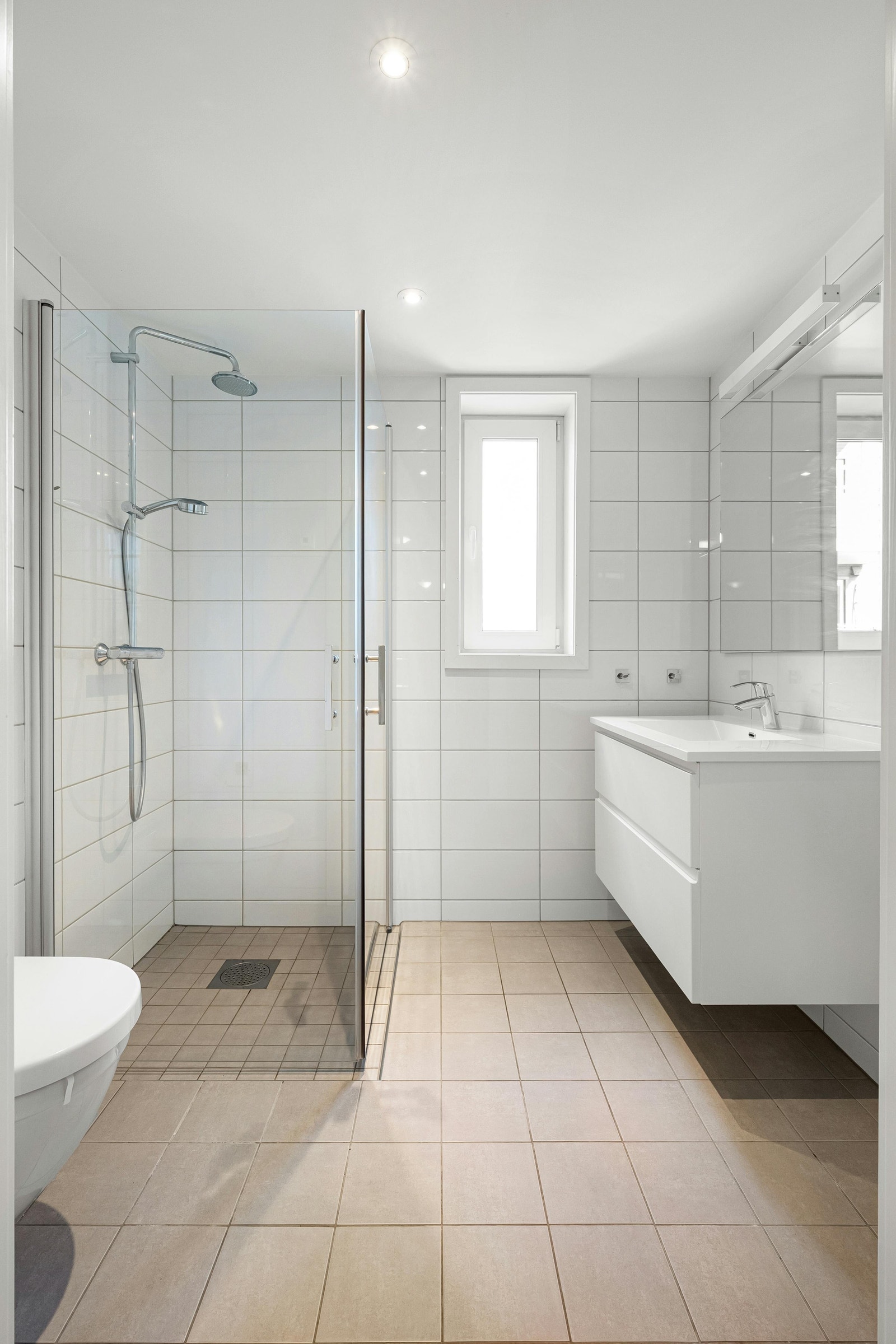 Pent flislagt bad med innfellbare dusjdører og opplegg for vaskemaskin Galleribilde