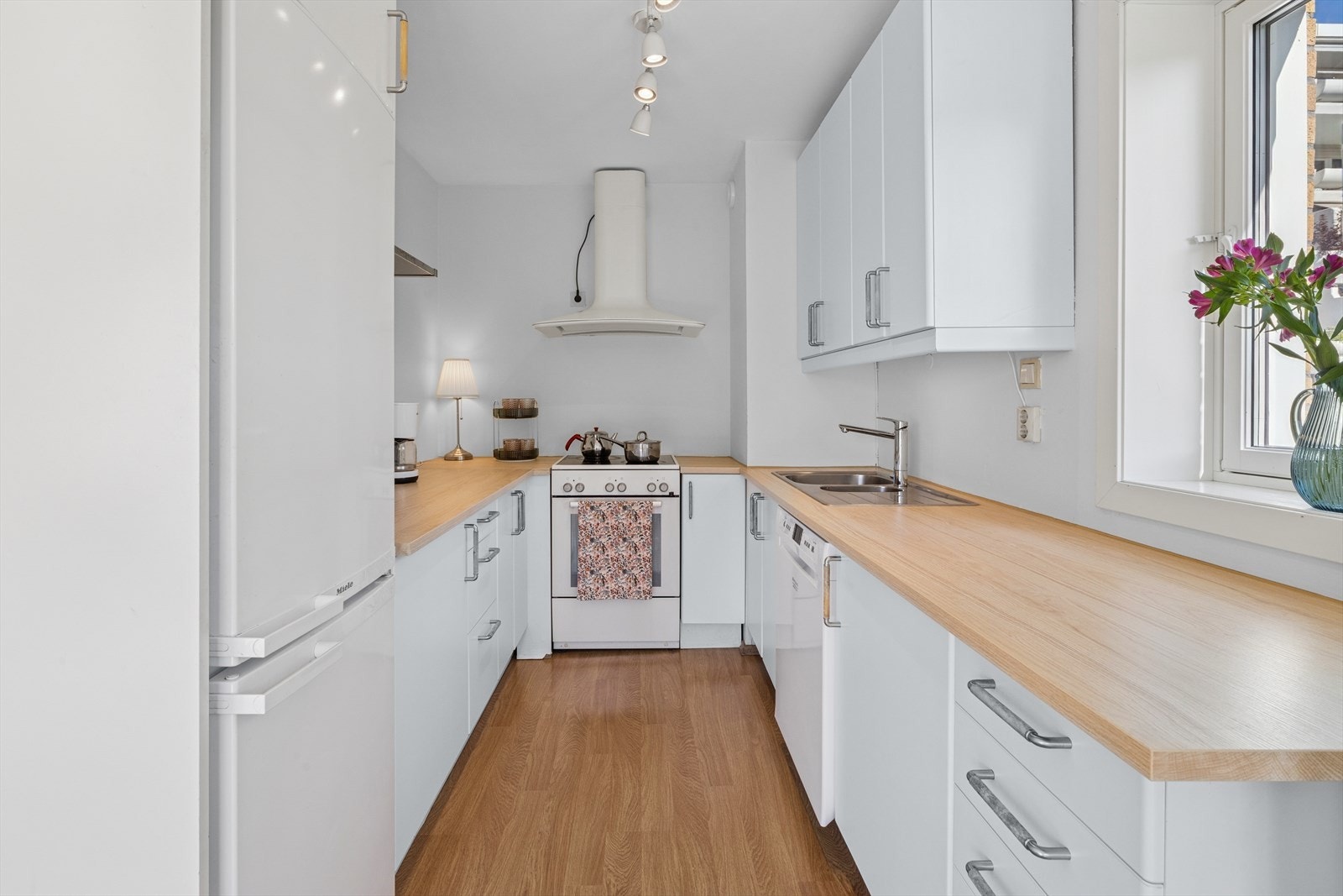 Kjøkkenet har hvit innredning med slette fronter og laminat benkeplate som gir et rent og tidløst uttrykk. Galleribilde