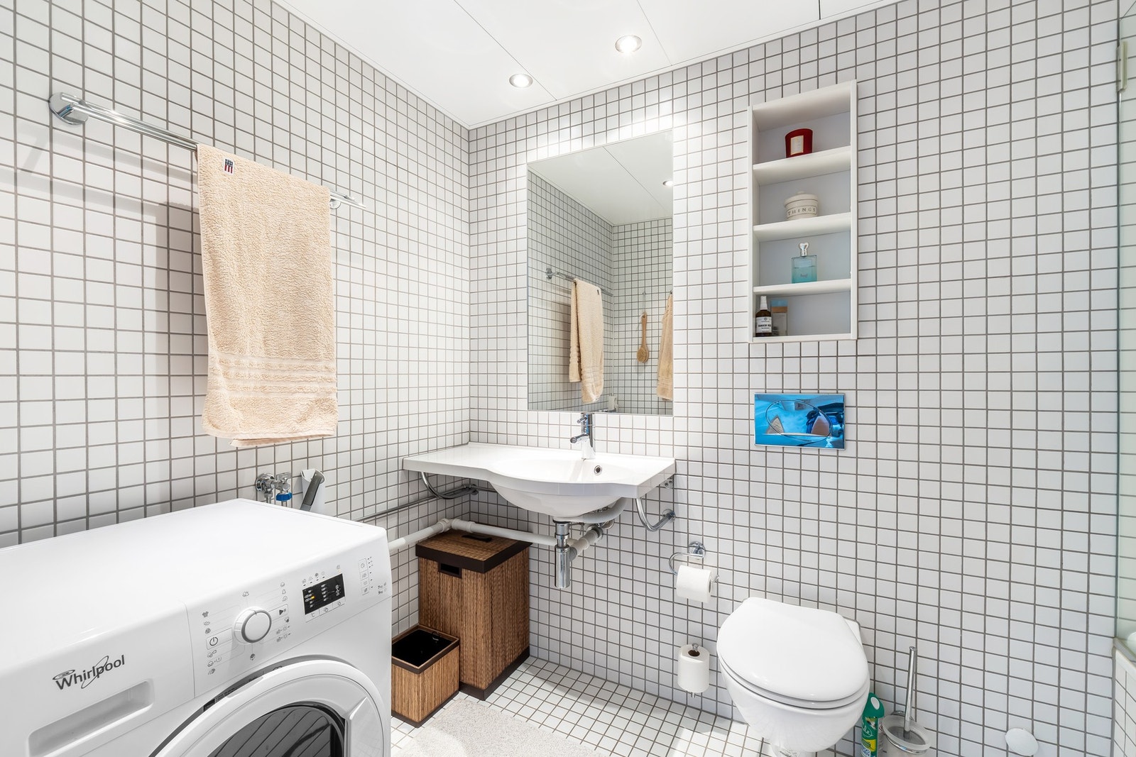 Hovedbadet er innredet med lyse gulvfliser med gulvvarme, flislagte vegger, downlights i taket og praktiske nisjer for oppbevaring av velværeprodukter. Galleribilde