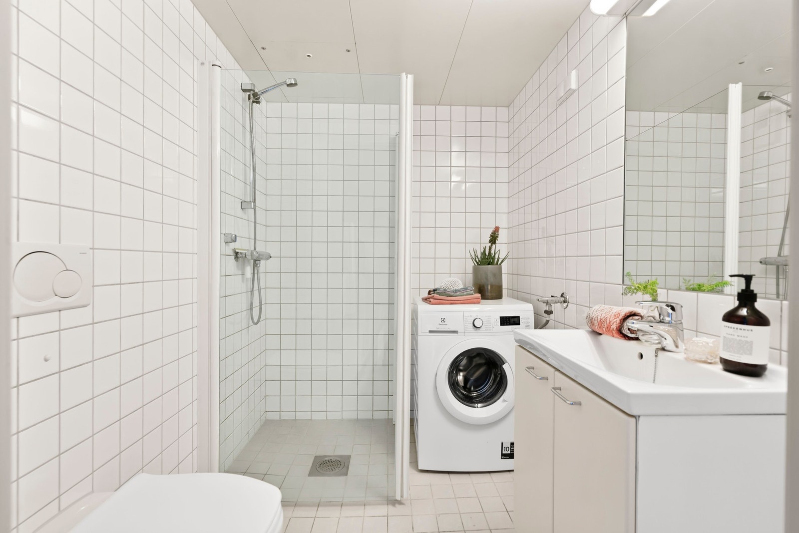 Praktisk tidløst bad fra 2007 med dusjhjørne, vegghengt WC, servant med underskap, speil med lys og opplegg for vaskemaskin. Galleribilde