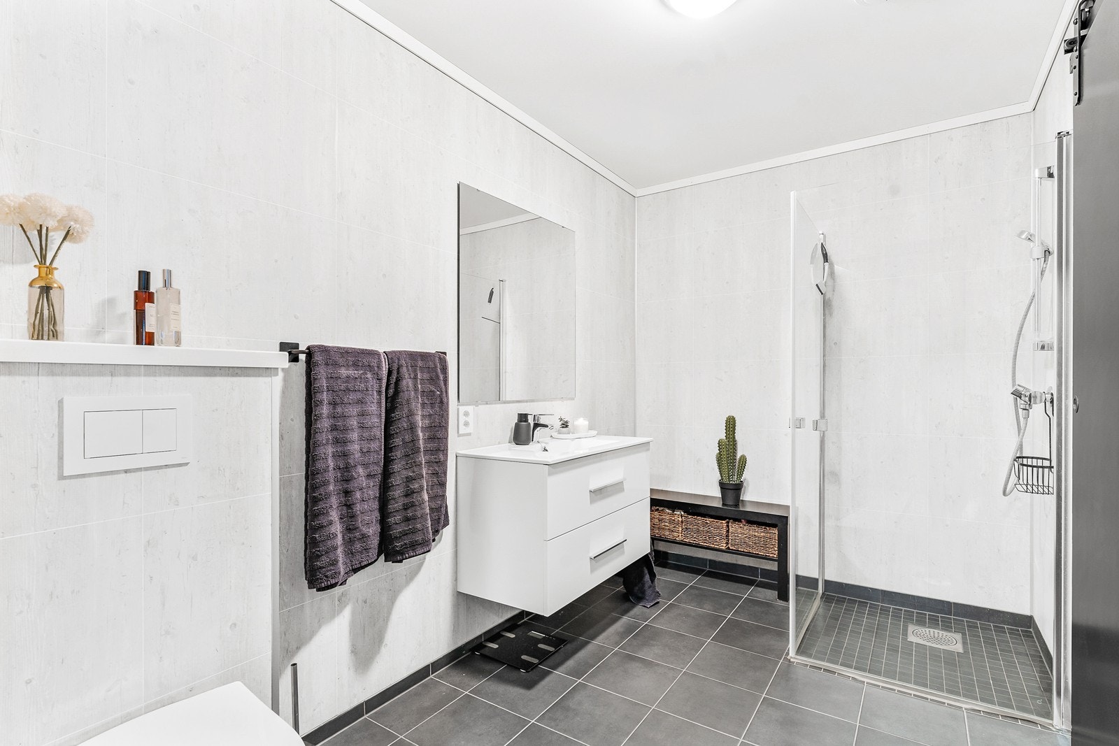 Badet er innredet med vegghengt toalett, baderomsinnredning med vask, dusjhjørne med glassvegger og opplegg for vaskemaskin. Galleribilde