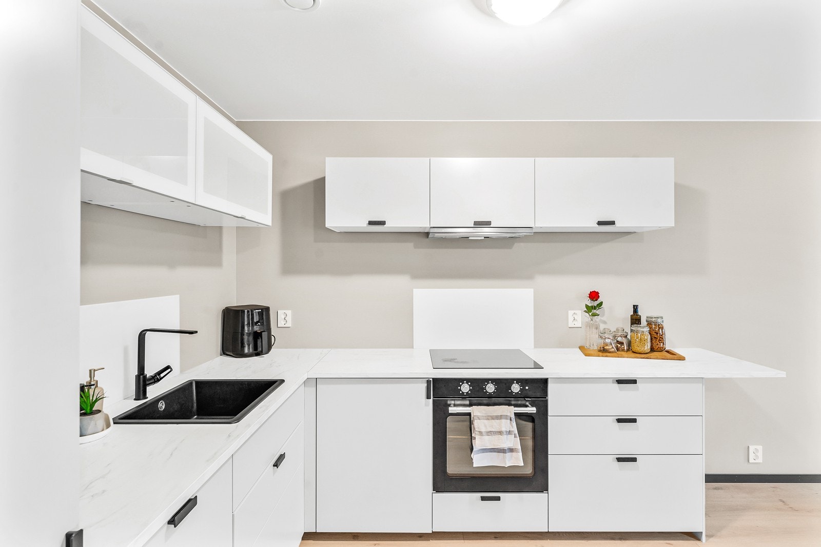 Kjøkkenfrontene er lyse og slette, med håndtak i sort metall. Galleribilde