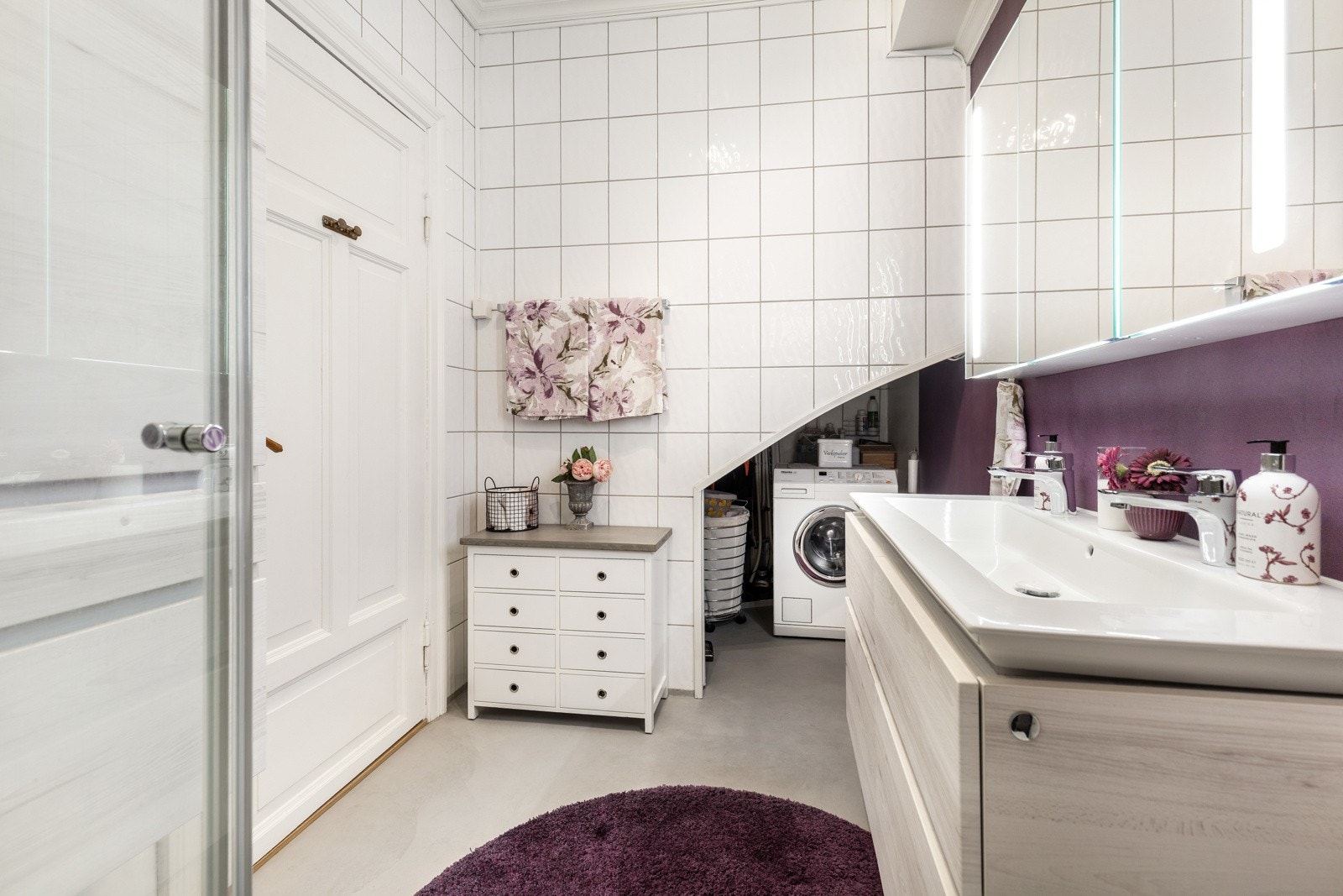 Videre er badet utstyrt med dusjkabinett, gulvmontert toalett og nisje i veggen med opplegg for vaskemaskin. Galleribilde