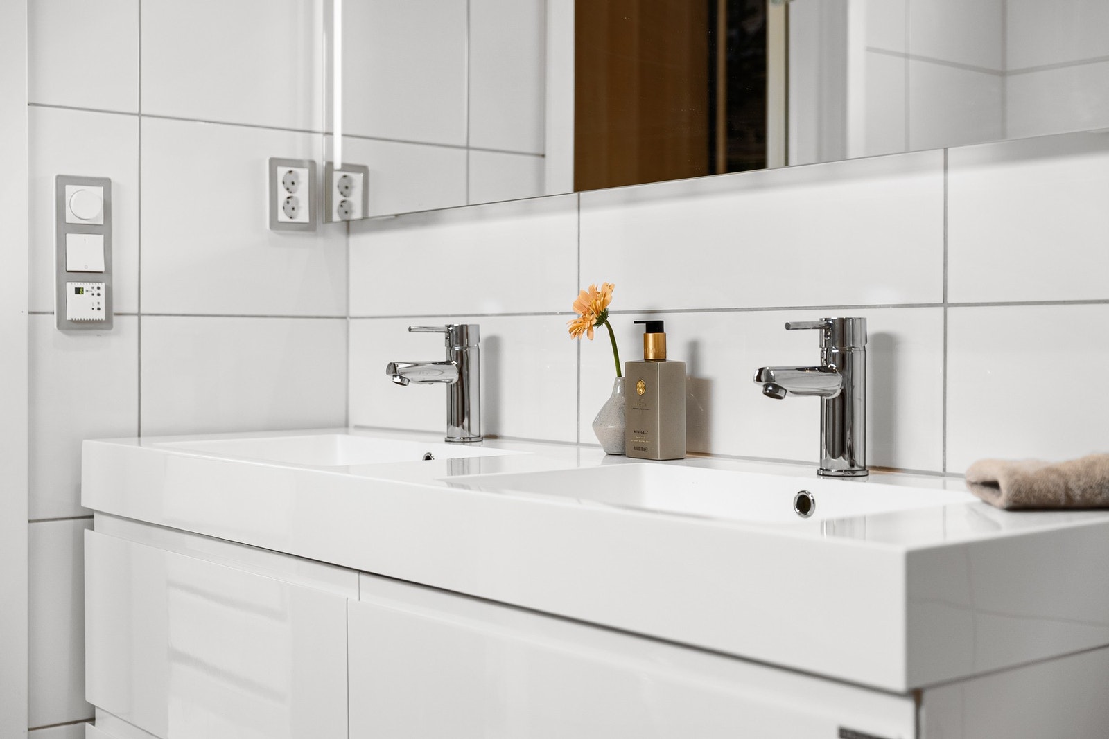 Innredet med servantinnredning med to servanter, speil med lys på vegg over servant, vegghengt toalett, frittstående badekar og dusjhjørne med svingbare glassdører. Galleribilde