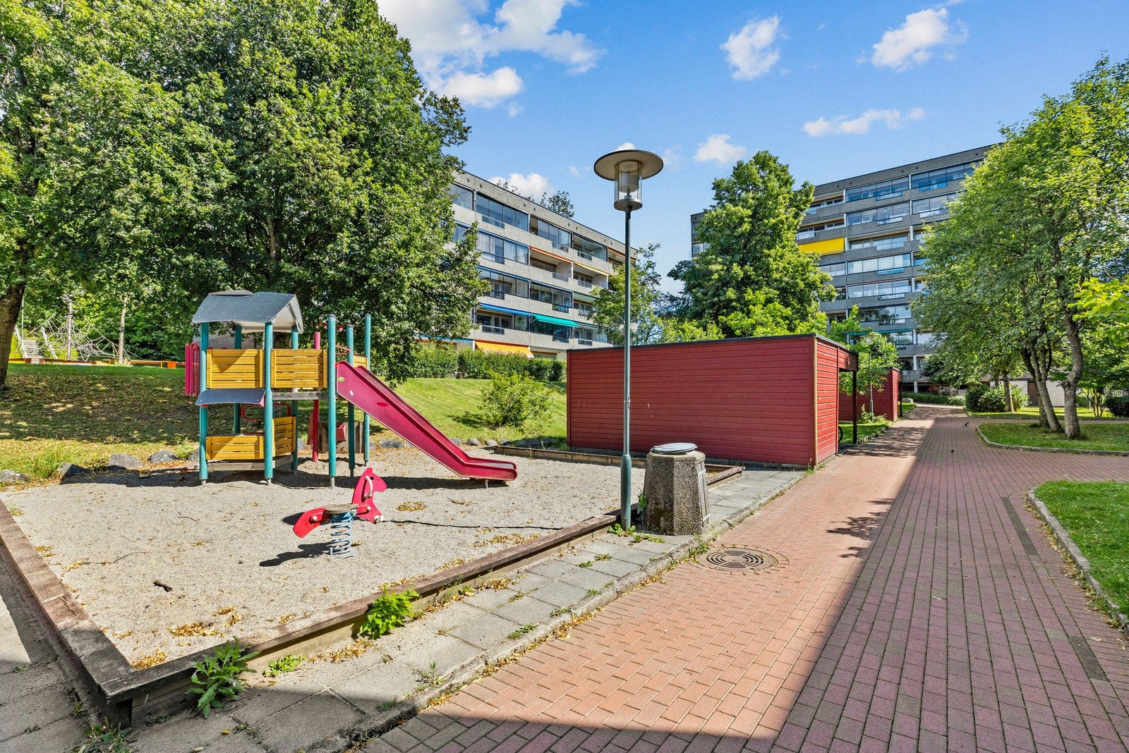 Her i borettslaget trives både store og små - med trygge lekeplasser og flotte uteområder der barna kan leke fritt og foreldre kan slappe av. Galleribilde