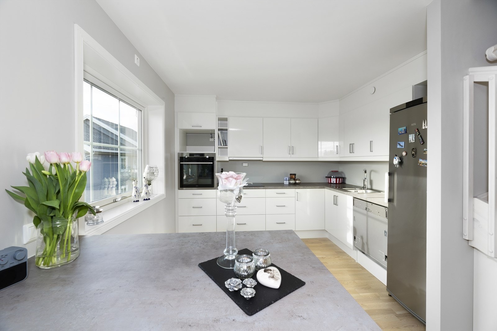 Klassisk og delikat kjøkkeninnredning med hvit høyglanset fronter og benkeplate av laminat. Galleribilde