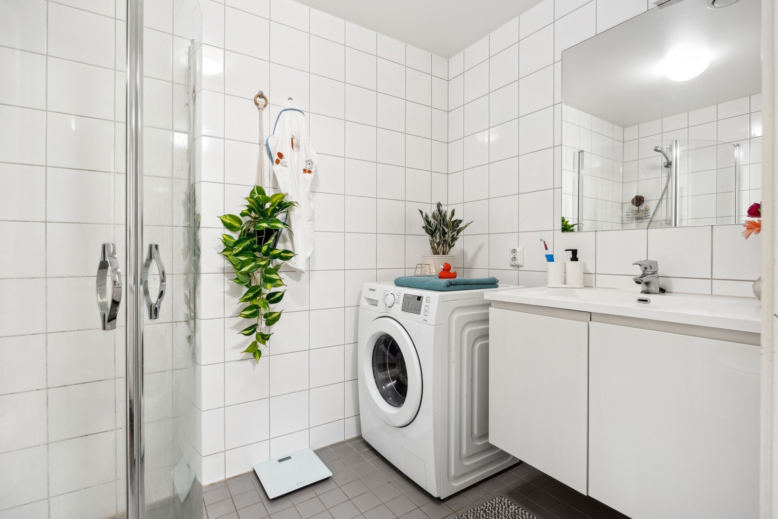 Badet har flislagt gulv med varme og opplegg for vaskemaskin. Galleribilde