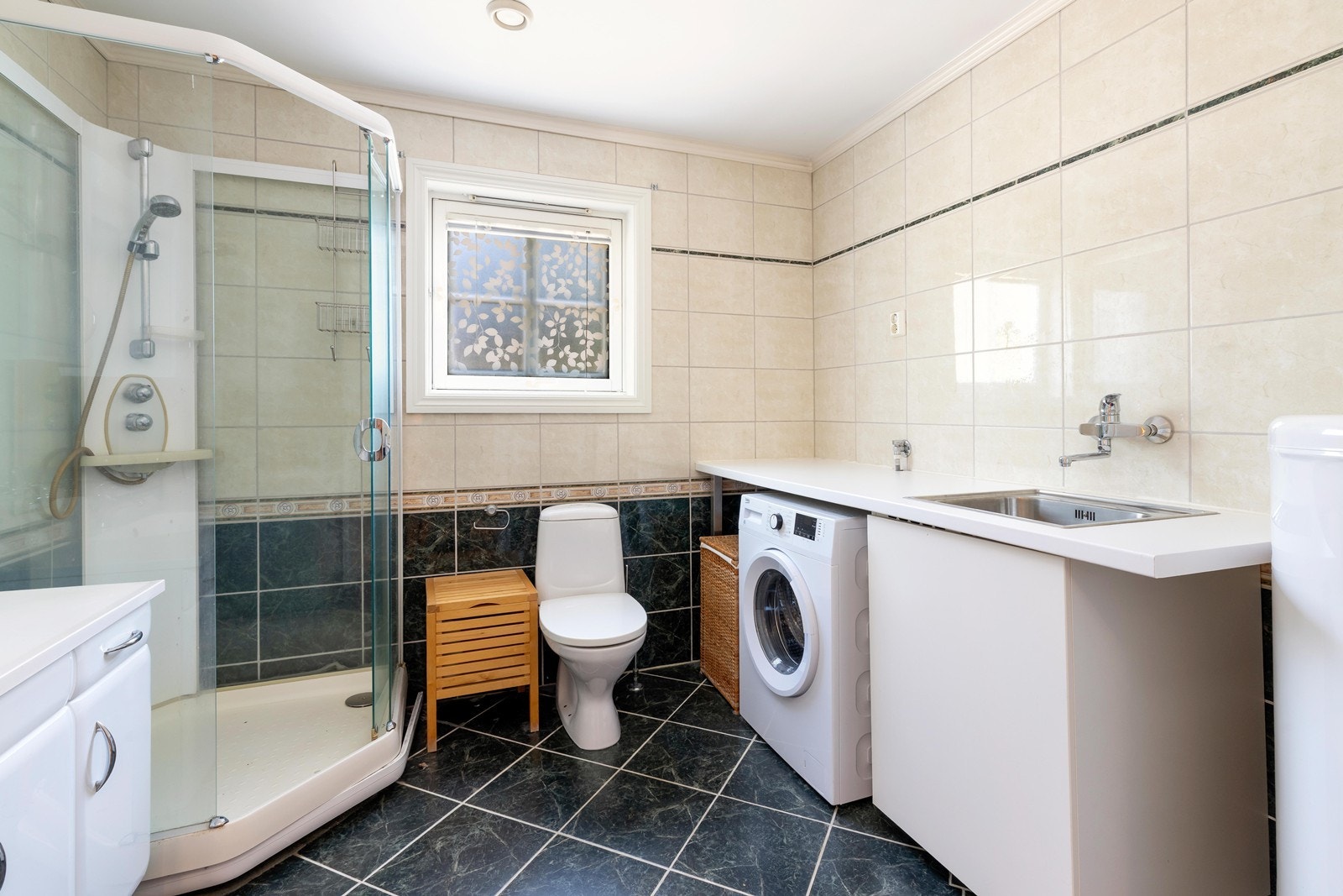 Flislagt bad med varme i gulv. Badet har dusjkabinett, toalett, og servant. Opplegg til vaskemaskin. Galleribilde