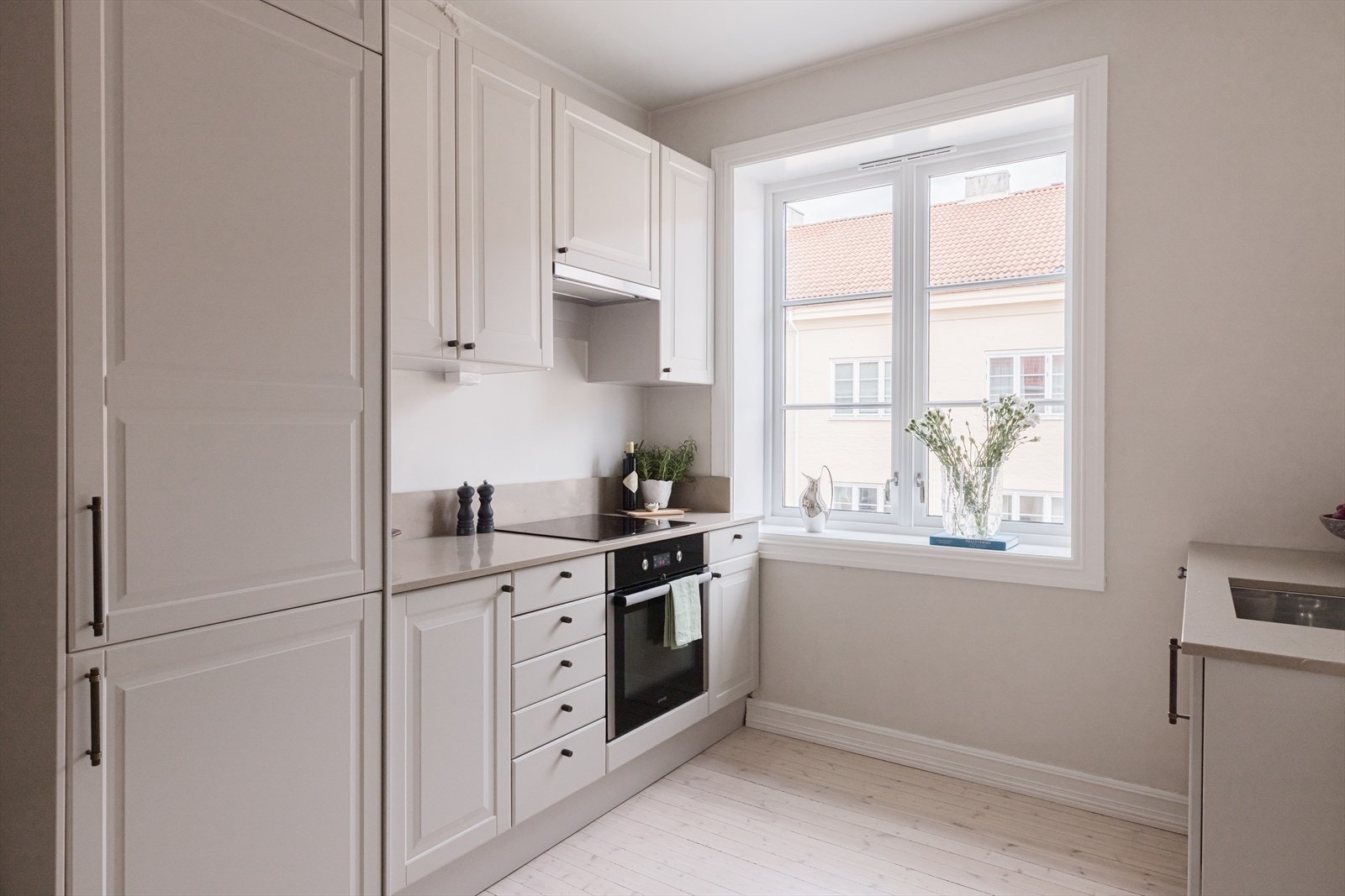 Pent kjøkken fra 2023 innredet med profilerte fronter, beslag fra Love Handles og benkeplate i komposittstein Galleribilde