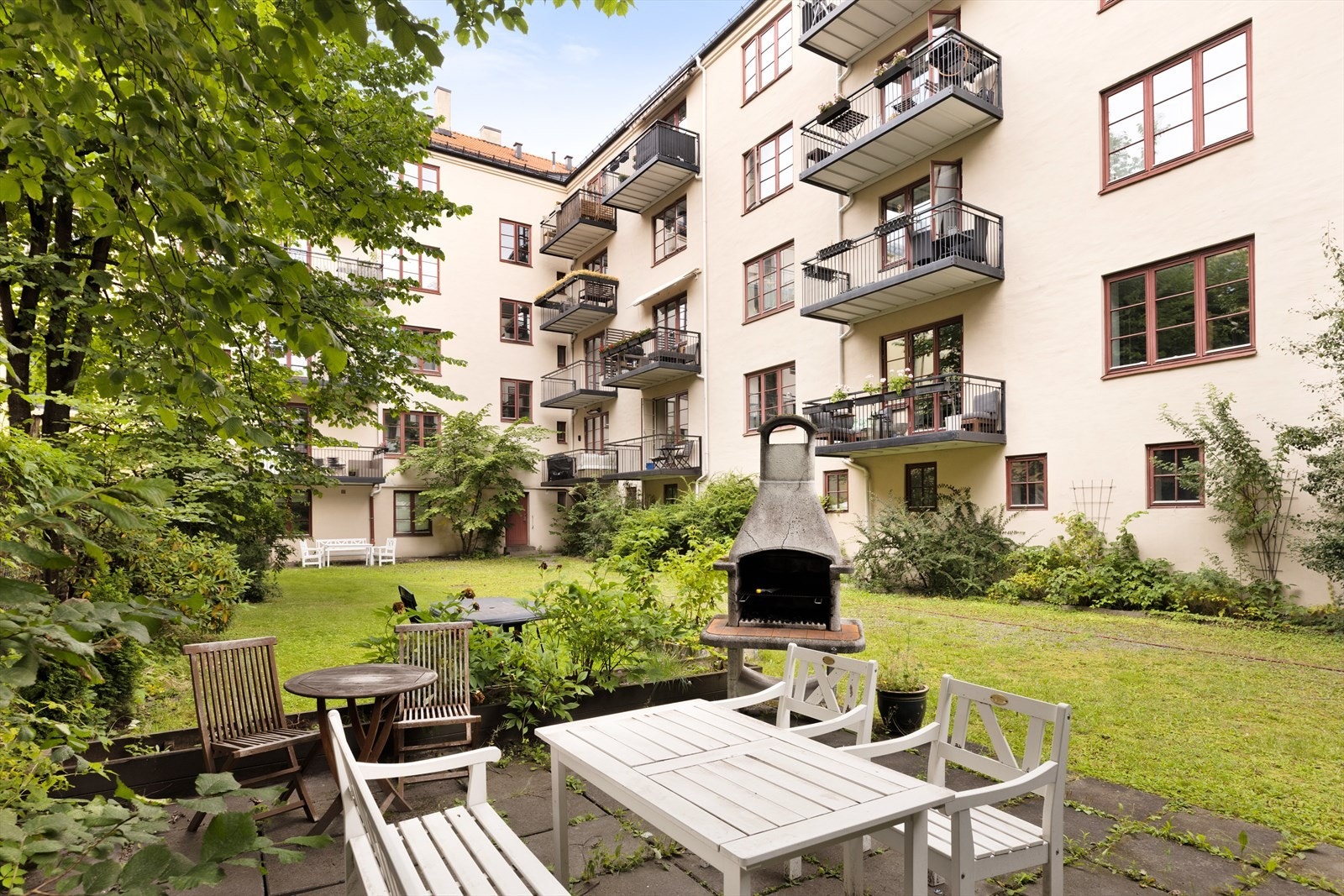 Idyllisk bakgård med frodig beplanting. Her finnes flere sittegrupper og grill til felles bruk Galleribilde