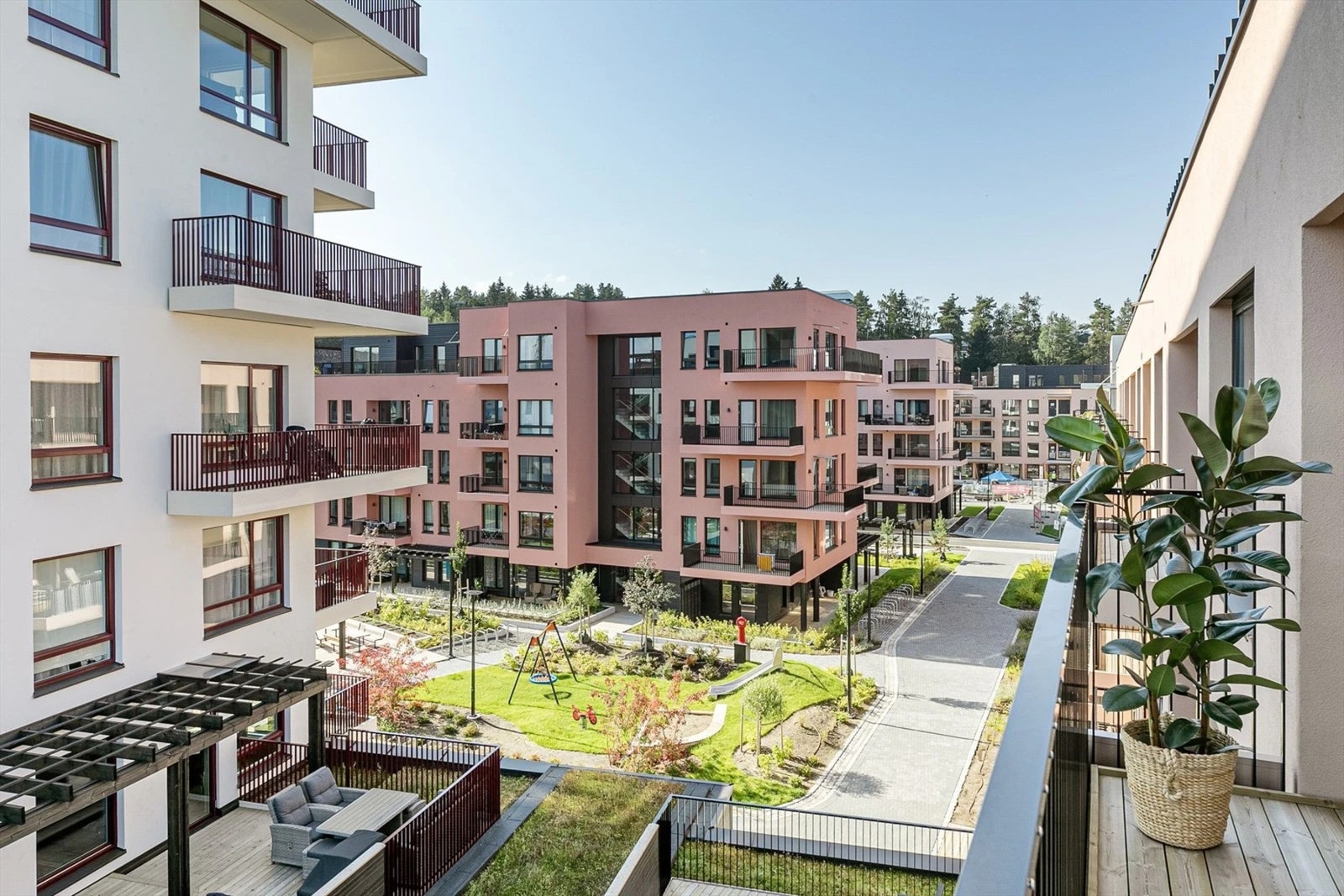 Felles bakgård med lekeplass, husker og sitteplasser for beboerne. Galleribilde