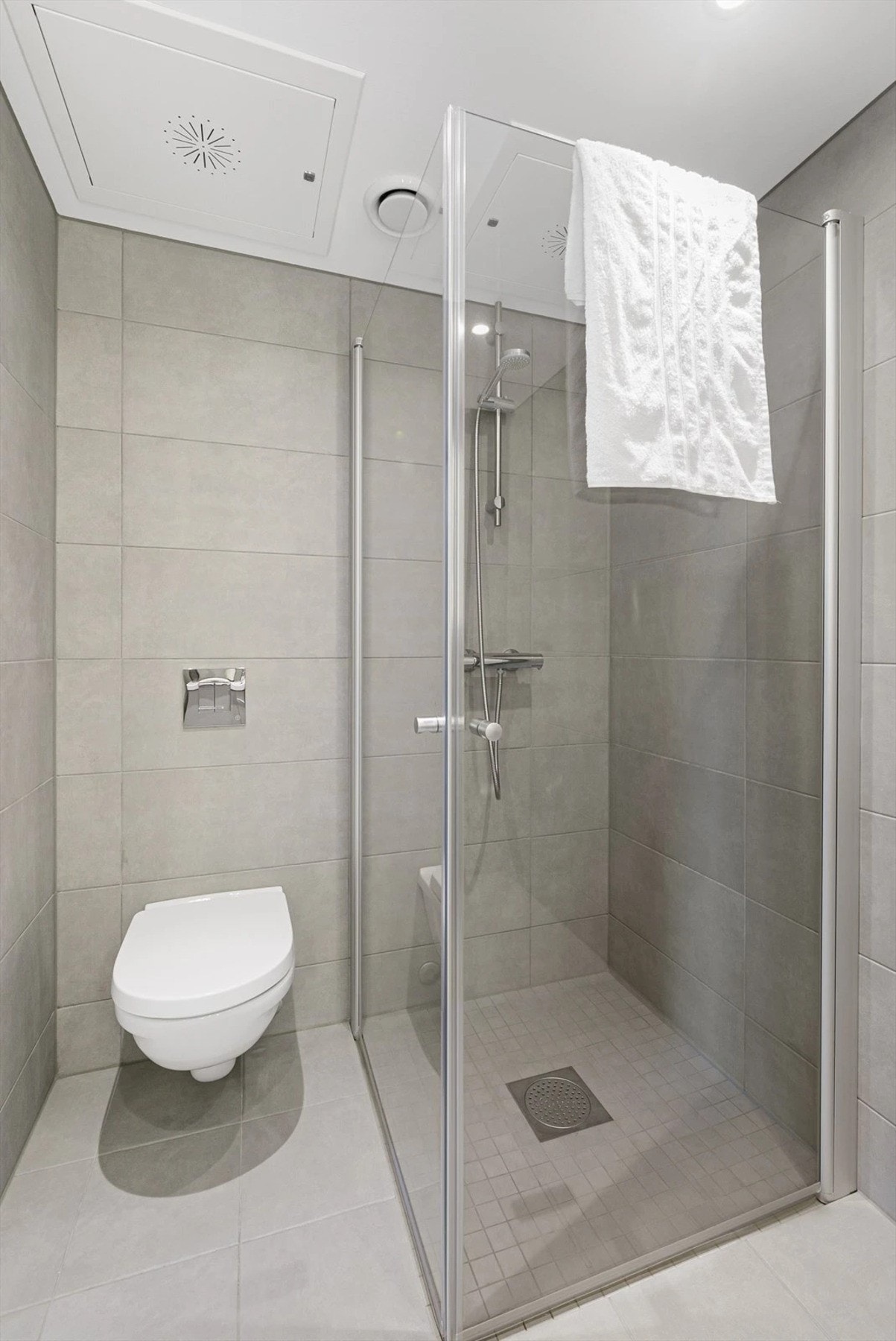 Dusjsone med glassdører og vegghengt toalett. Galleribilde