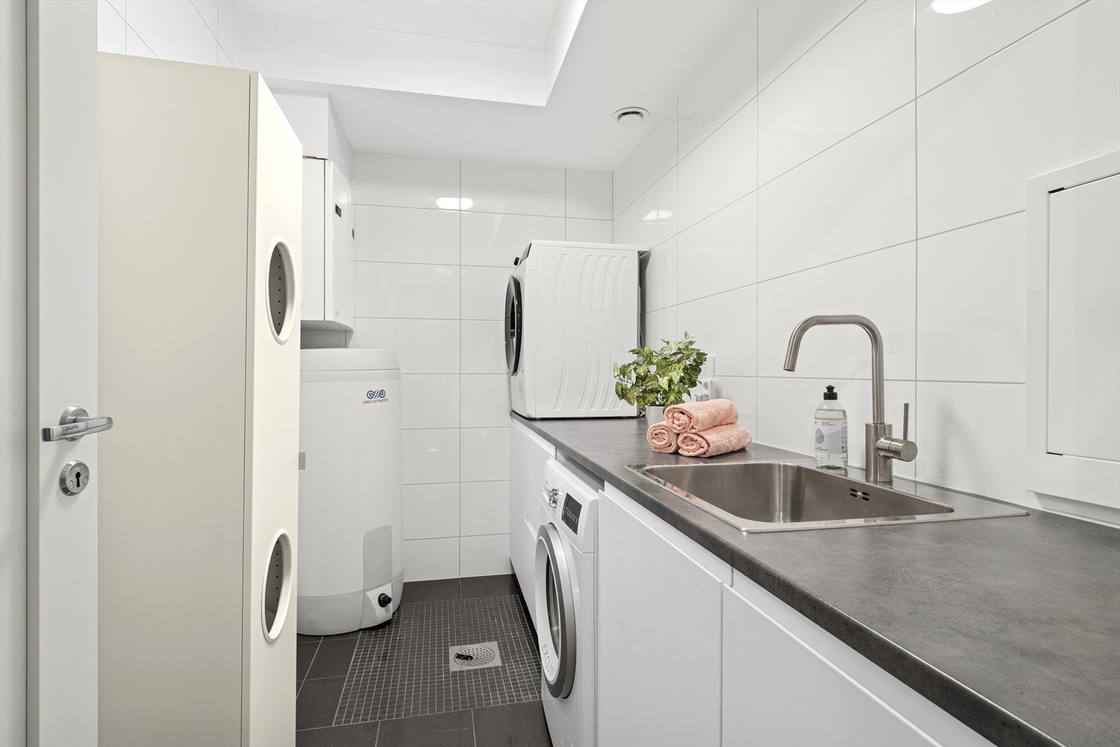 Innredning med nedfelt utslagsvask og opplegg for vaskemaskin. Rommet har elektriske varmekabler i gulv og balansert ventilasjon. Galleribilde