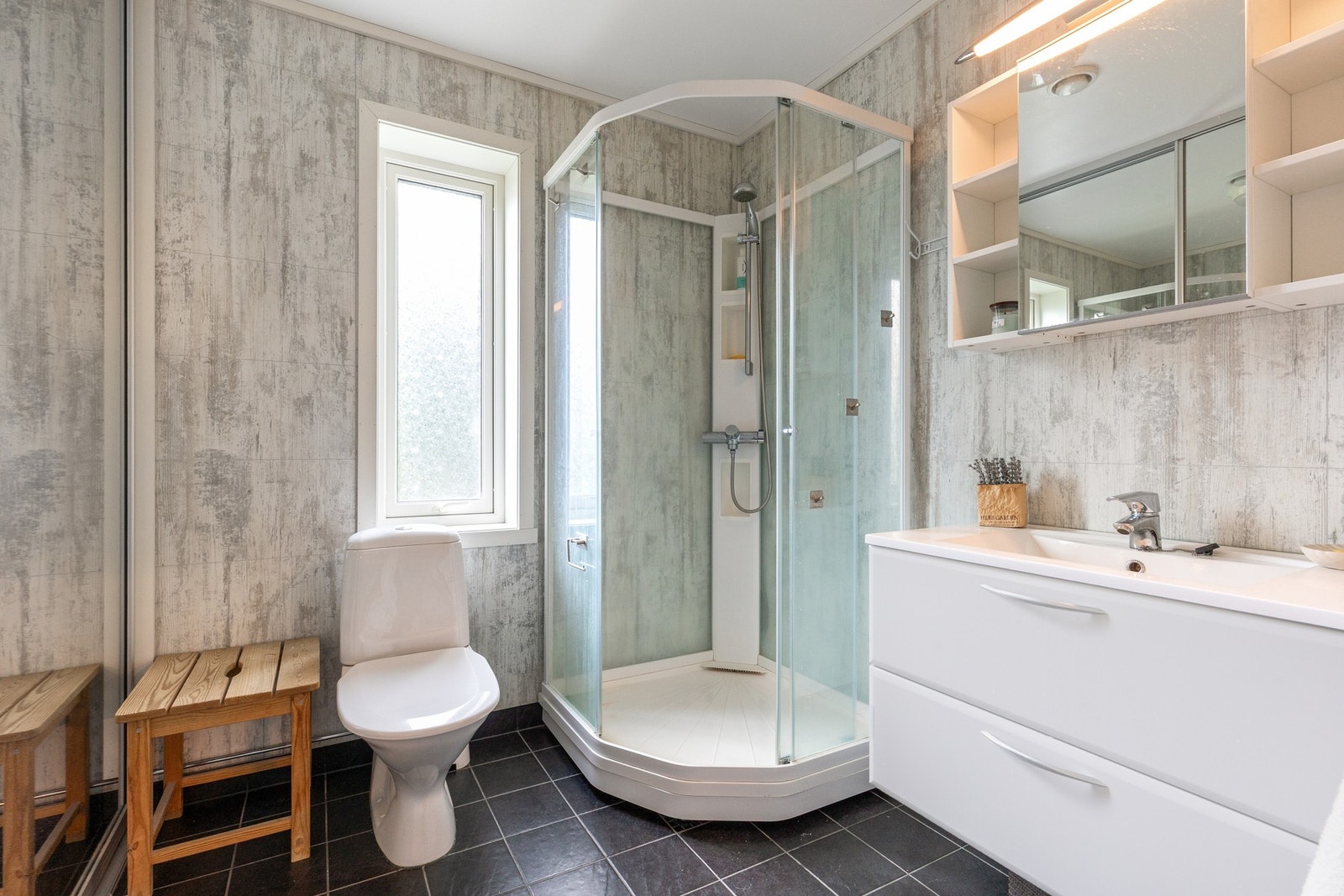 Delikat baderom bestående av servant med underskuffer, dusjkabinett og toalett Galleribilde