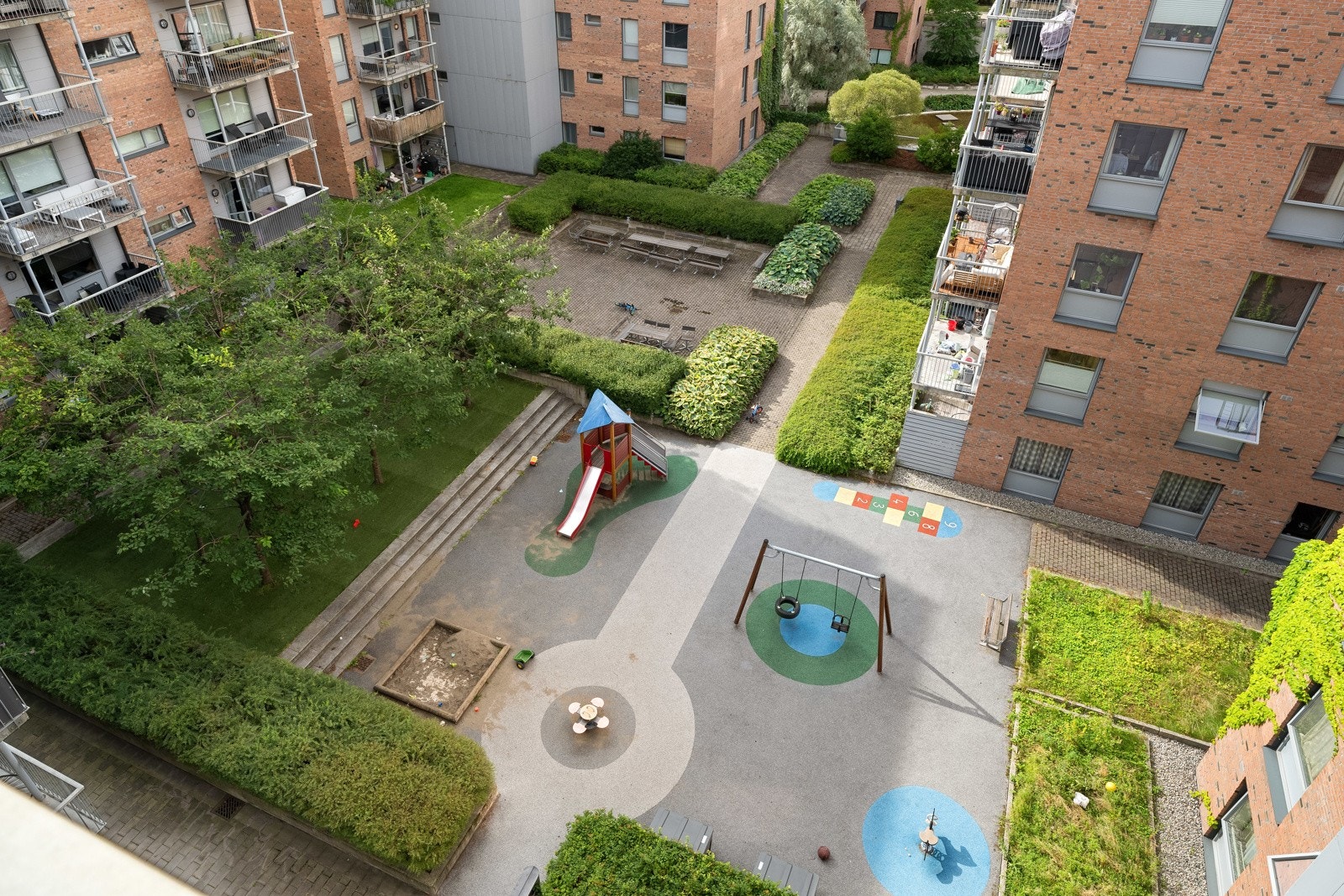 Utsyn ned mot lukket gårdsrom med lekeplass fra balkongen Galleribilde