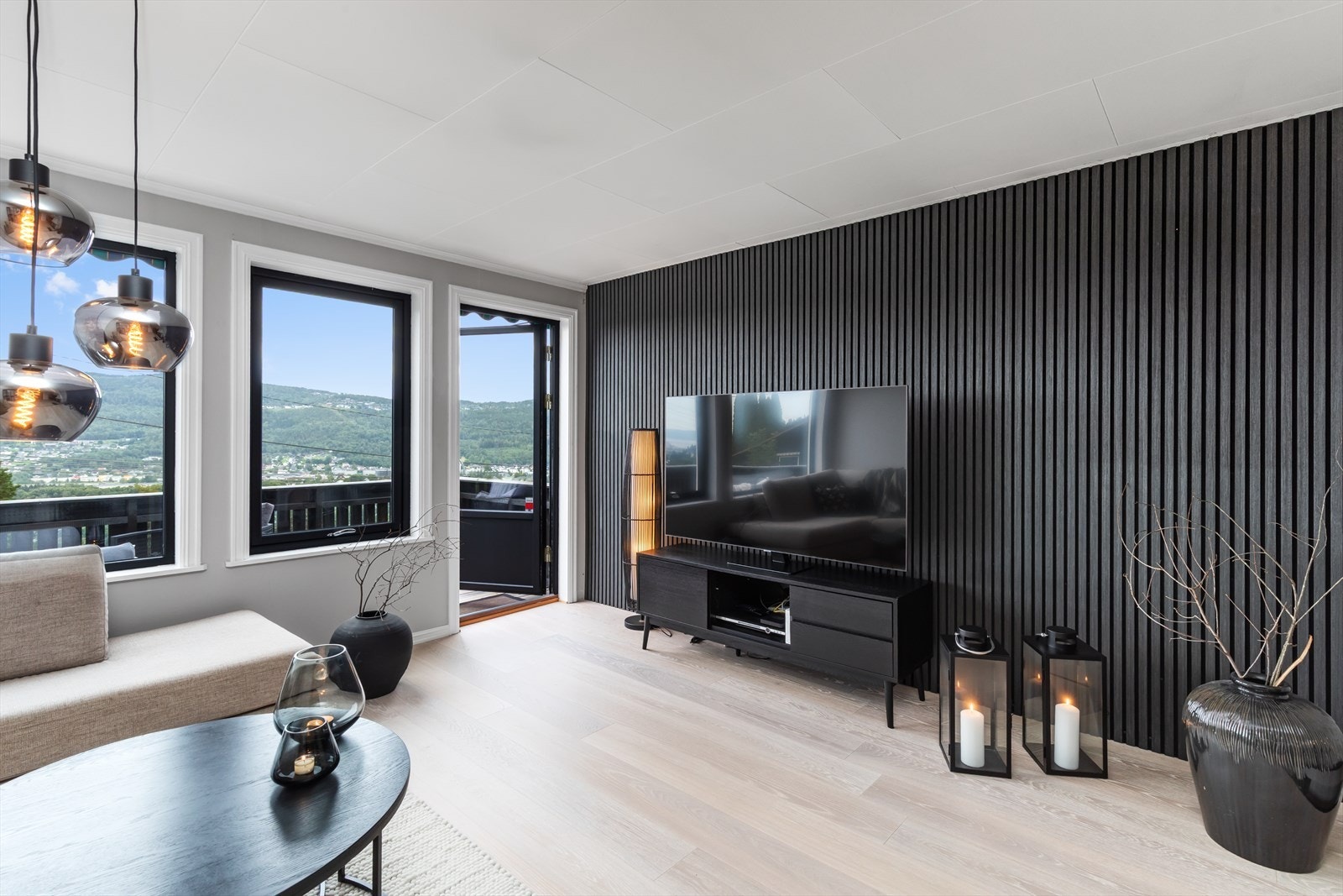 Stuen fremstår som moderne med sorte detaljer og spilevegg Galleribilde