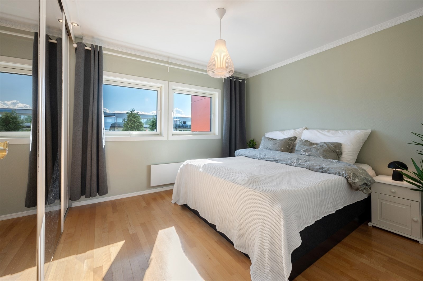 Romslig hovedsoverom med lyse farger og praktisk skyvedørsgarderobe. Galleribilde