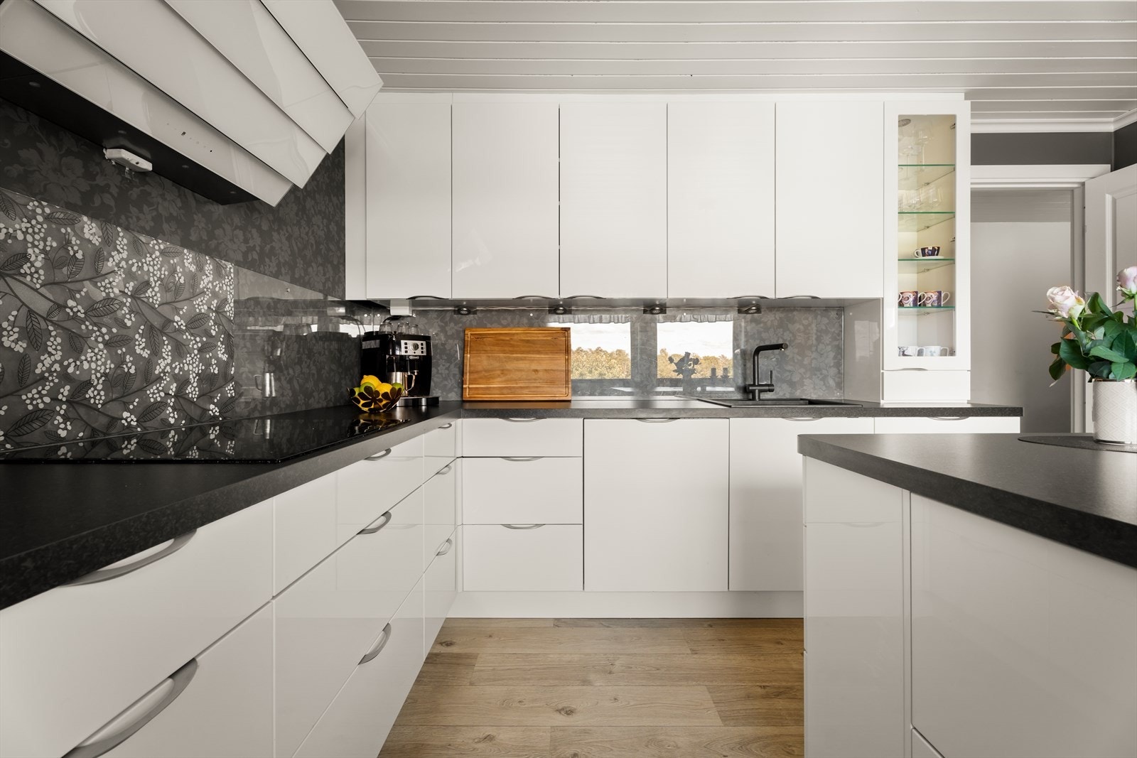 Det er montert stilrene glassplater mellom benk og overskap, noe som både beskytter veggen og gir et elegant preg Galleribilde