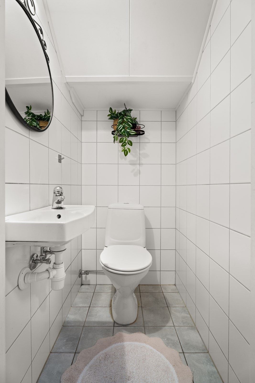 Toalettrommet ligger vegg i vegg med badet. Rommet har Takessplater i taket samt fliser på både vegger og gulv, noe som gir en helhetlig og lettstelt overflate Galleribilde