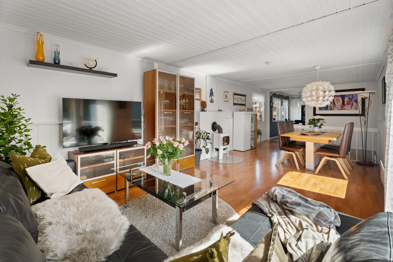 Stuen ligger i en delvis åpen løsning mot kjøkkenet og er innredet med både sofagruppe og spisebord, noe som gjør det enkelt å innrede både for hverdagsliv og sosiale sammenkomster Galleribilde