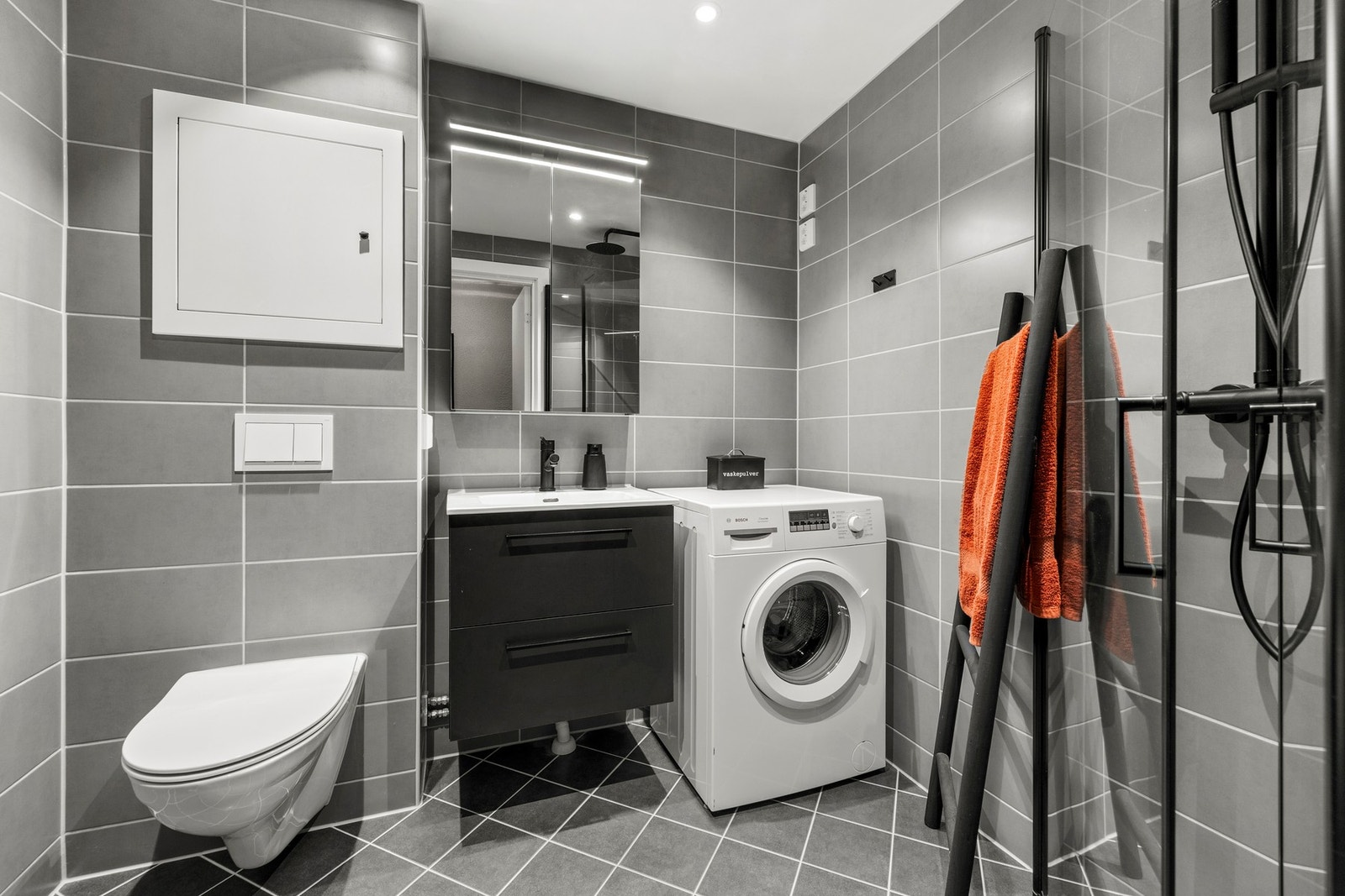 Moderne baderom fra 2022 som er pusset opp i regi av borettslaget. Badet har grå fliser, downlights og veggmontert toalett. Galleribilde