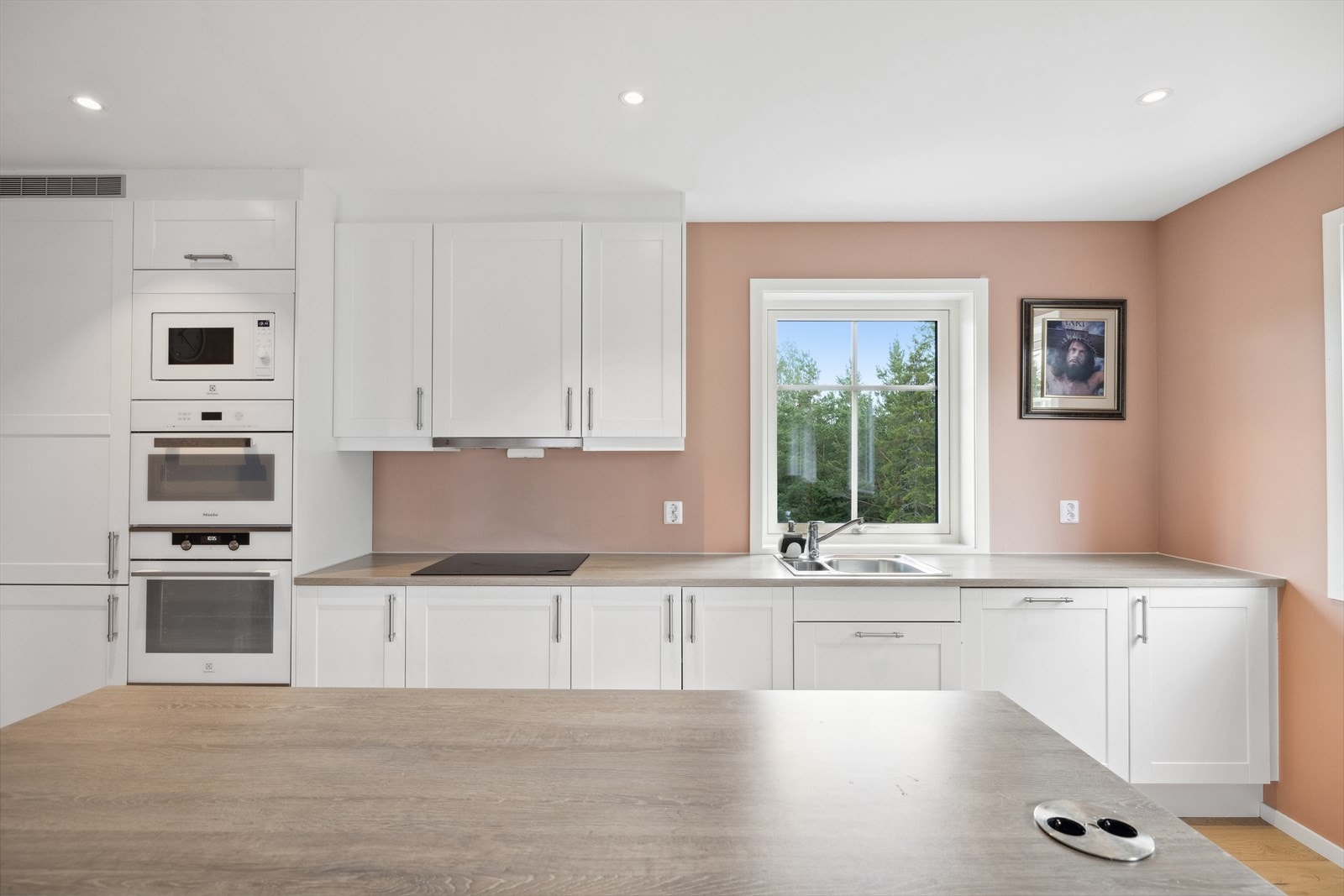 Kjøkkenet har nøytral innredning med hvite profilerte fronter og benkeplate i laminat. Galleribilde