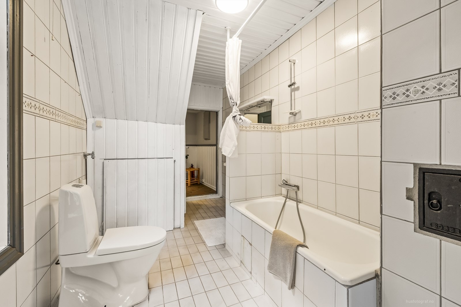 Bad med toalett, badekar og røropplegg til vaskemaskin. Galleribilde