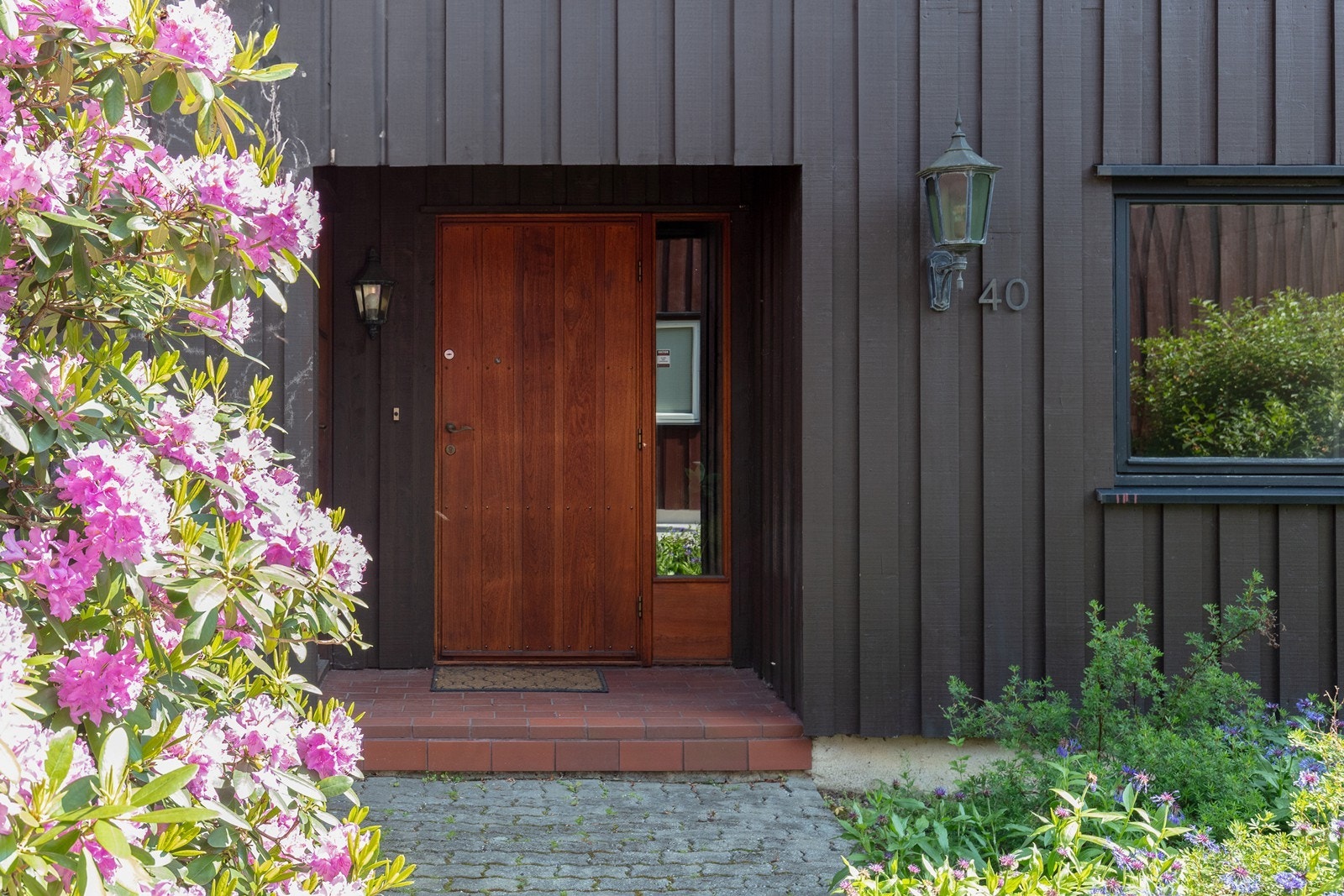 Pent inngangsparti med belegningsstein og prydbusker. Galleribilde