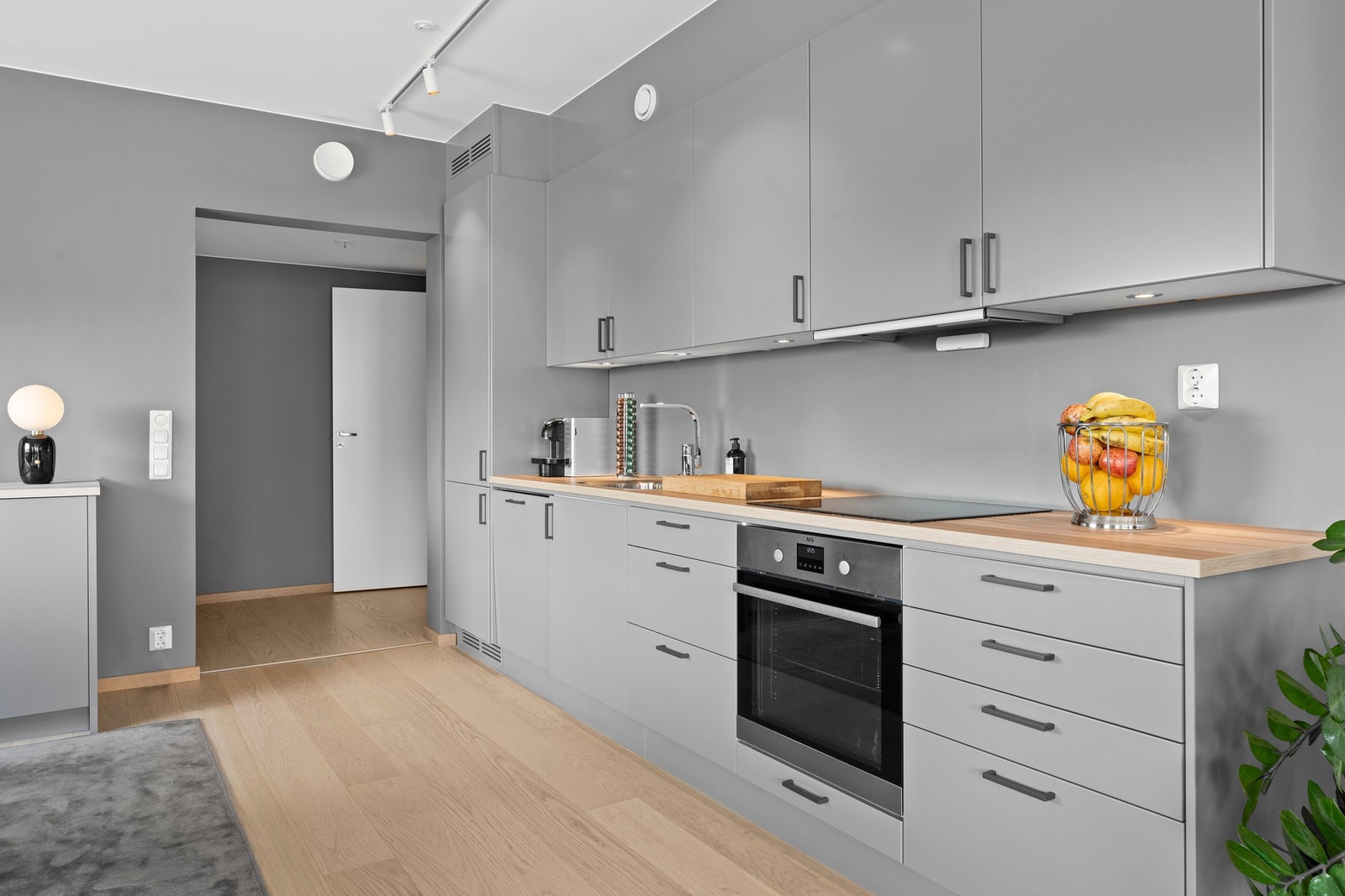 Kjøkkenet har en stilren og moderne innredning med grå, slette fronter og laminerte benkeplater med nedfelt oppvaskkum. Galleribilde