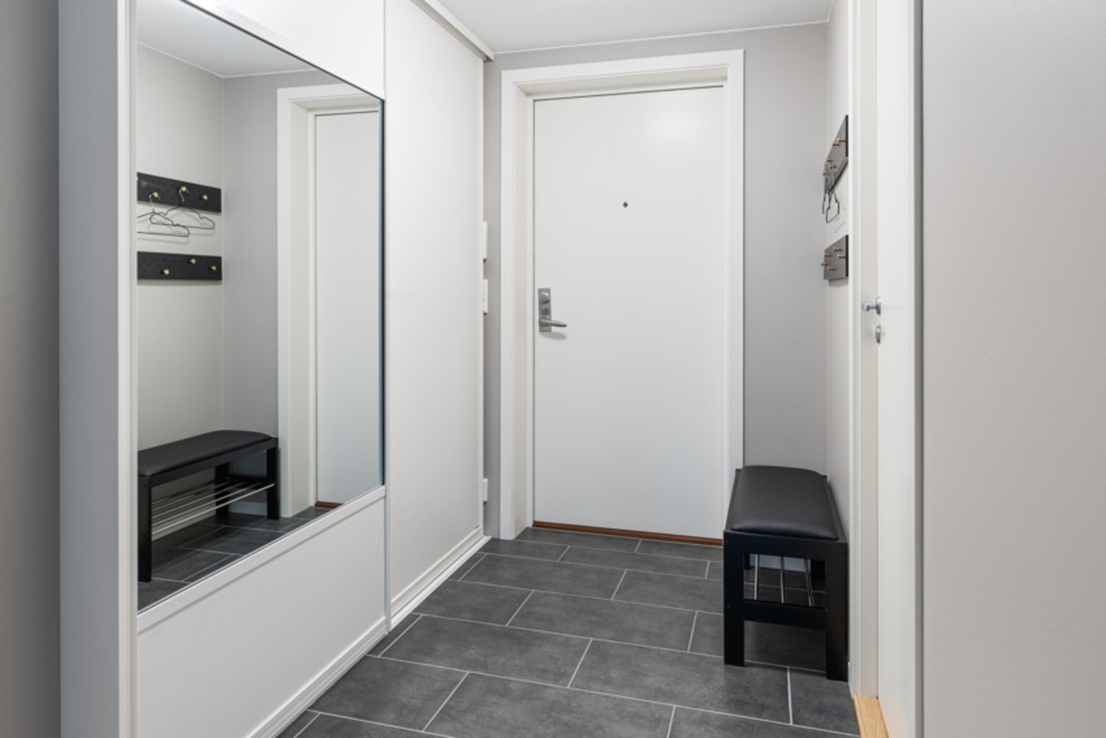 Fra første skritt merker man den gode følelsen av nytt byggeår kombinert med arbeid utført av fagfolk. I gangen har dagens eier etablert en smart skyvedørsløsning som sørger for god plass til klær og sko. Galleribilde