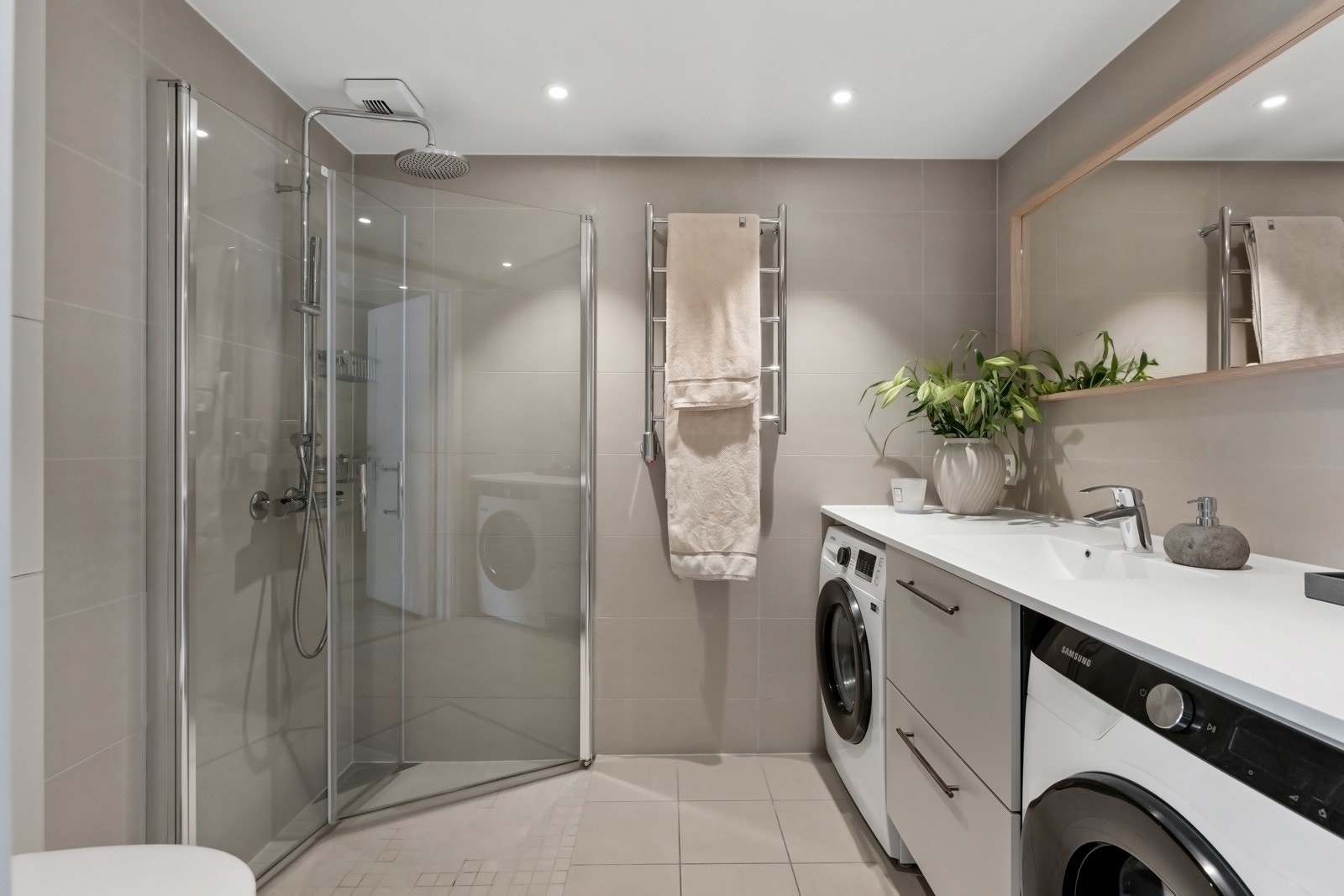 Badet er en prefabrikkert baderomsmodul fra 2022 og fremstår lekkert og moderne. Flislagte overflater, vannbåren gulvvarme og innfelte downlights i himling. Galleribilde