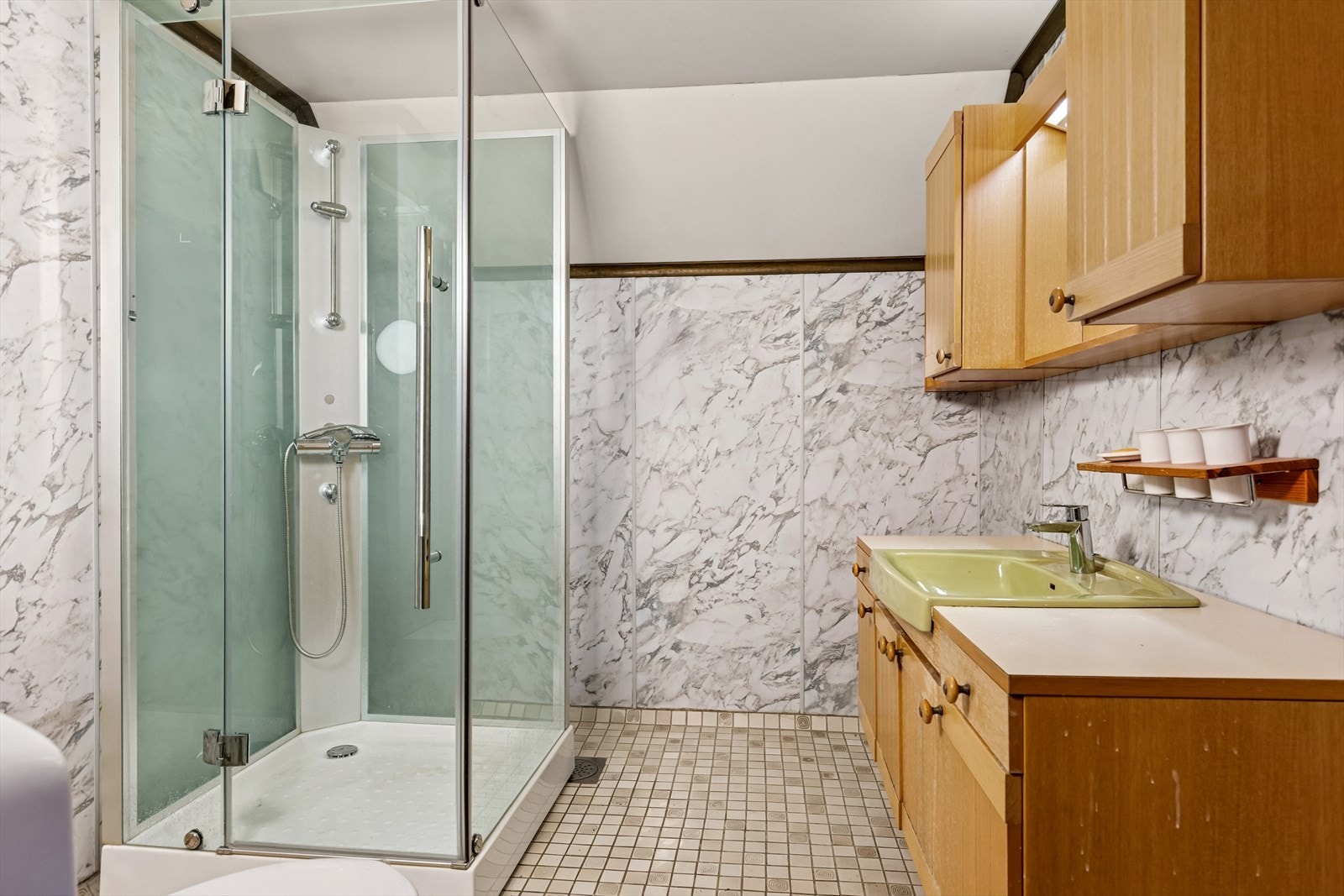 Bad i 2. etasje med flislagt gulv på betong, vegger med baderomspanel og malte plater i himlingen. Rommet har servant, wc og dusjkabinett, samt elektriske varmekabler og ventil på vegg. Våtrommet må oppgraderes for å tåle normal bruk etter dagens krav. Galleribilde