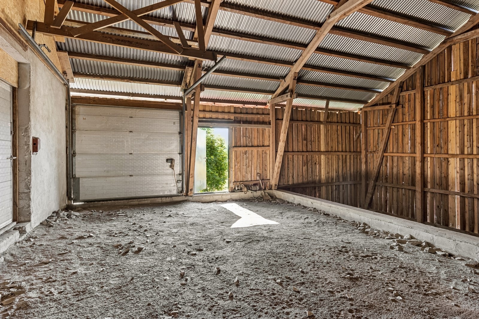 Luftig og enkel innvendig løsning med grusgulv og synlige bjelker -egnet for landbruksformål eller lagring. Galleribilde