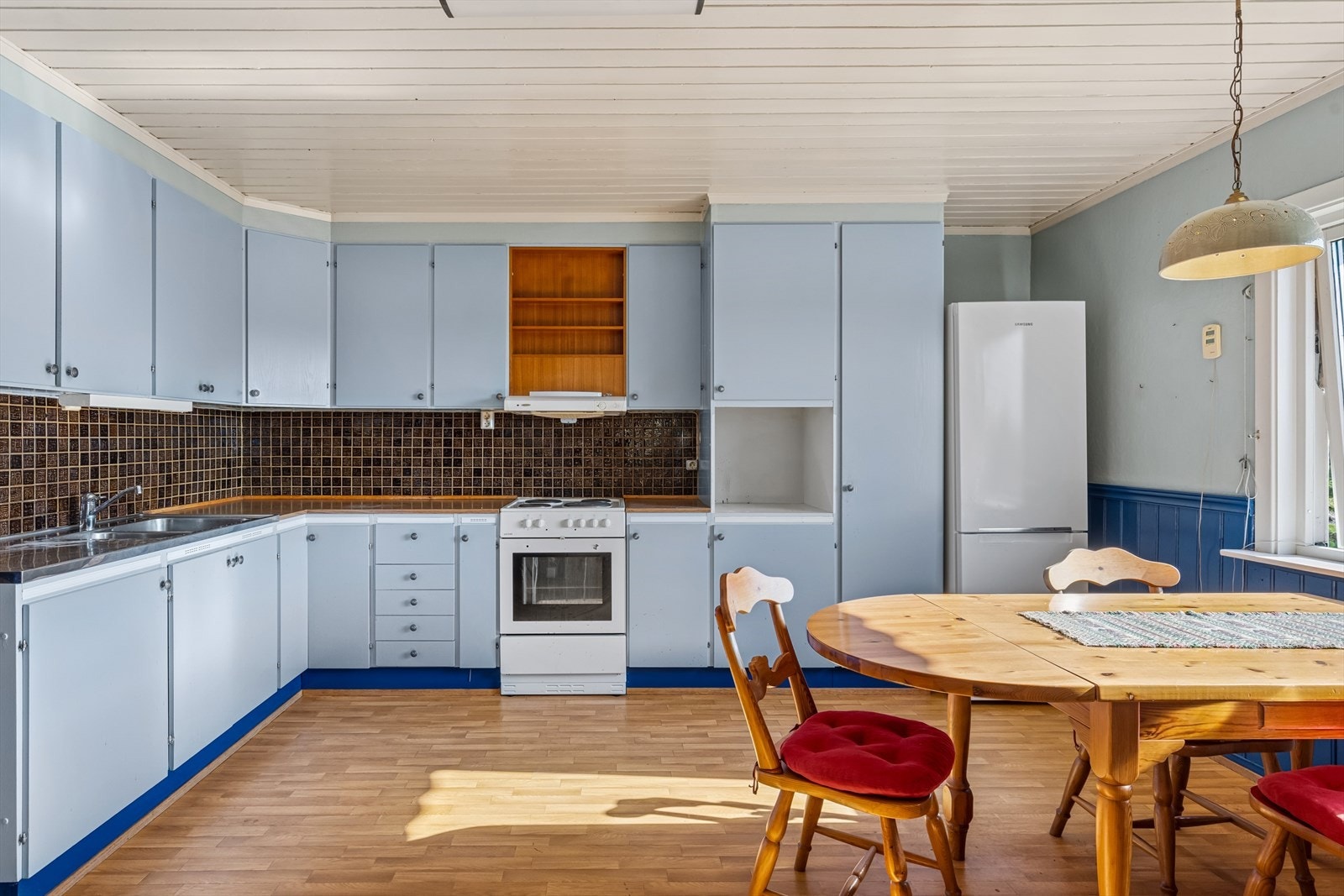 Kjøkkenet har innredning fra 1970-tallet med malte skrog og fronter av trefiberplater, benkeplate med høytrykkslaminert overflate og benkebeslag i rustfritt stål. Galleribilde