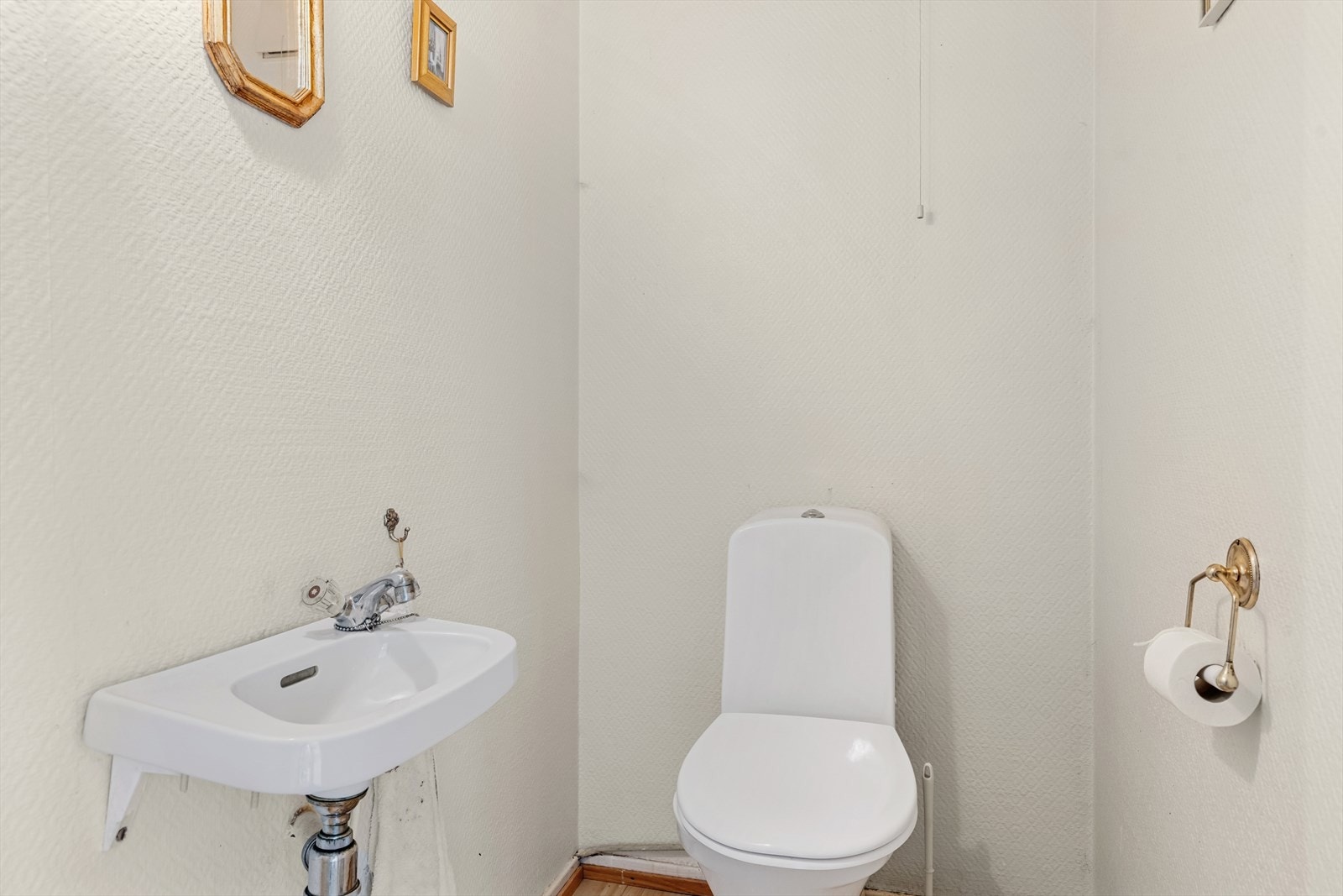 Toalettrom i 1. etasje med laminatgulv, malt strietapet på vegg og panel i himlingen. Inneholder servant og wc, sistnevnte byttet i senere år. Galleribilde