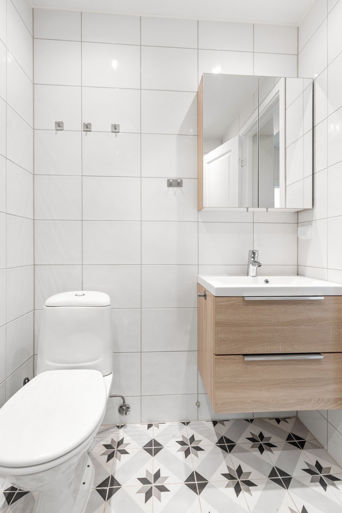 Rommet er innredet med dusjhjørne med glassdører, gulvstående toalett og innredning med nedsunket servant med speilskap Galleribilde