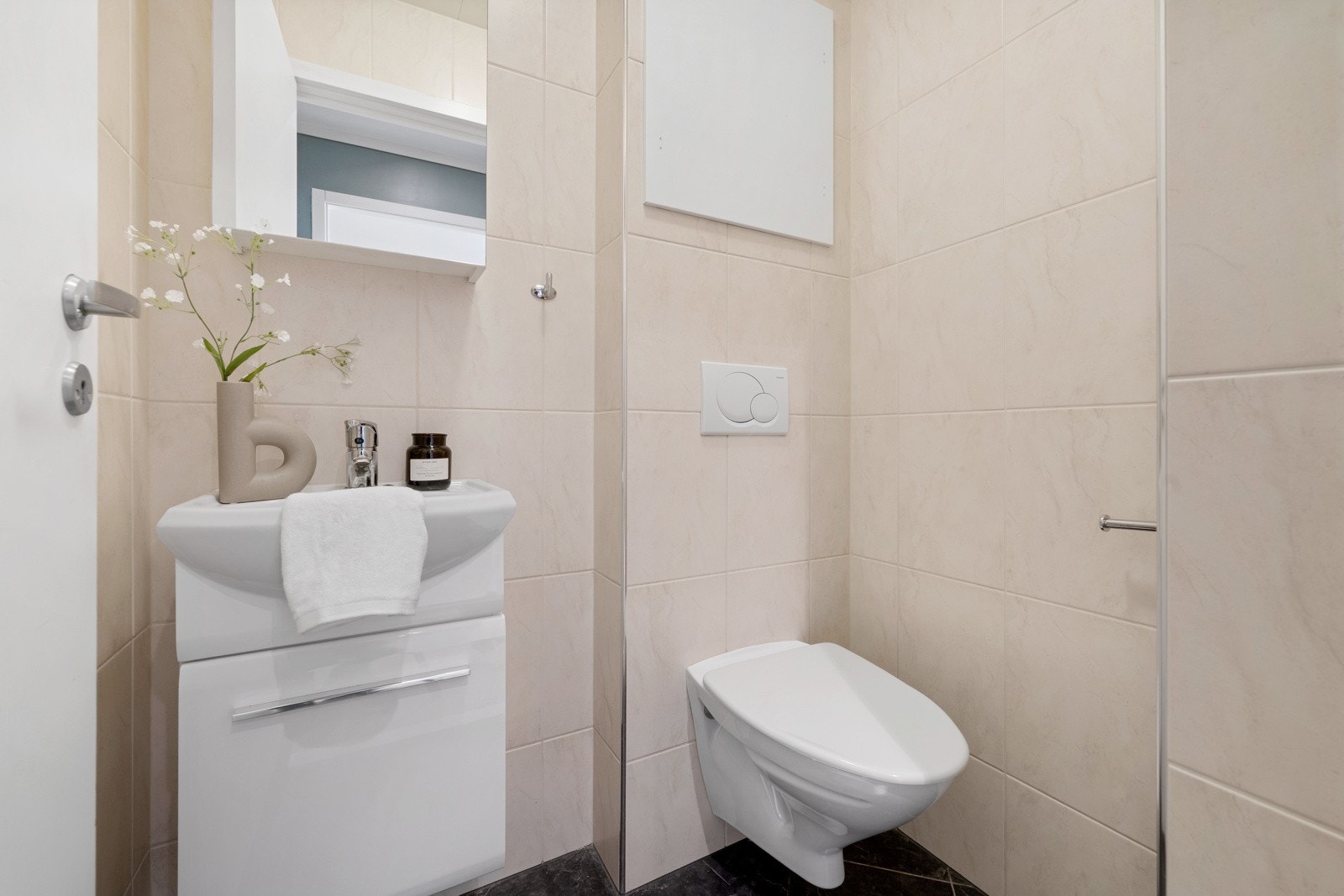 Lyst og pent toalettrom med flis på gulv og vegger samt tak ess i himling Galleribilde