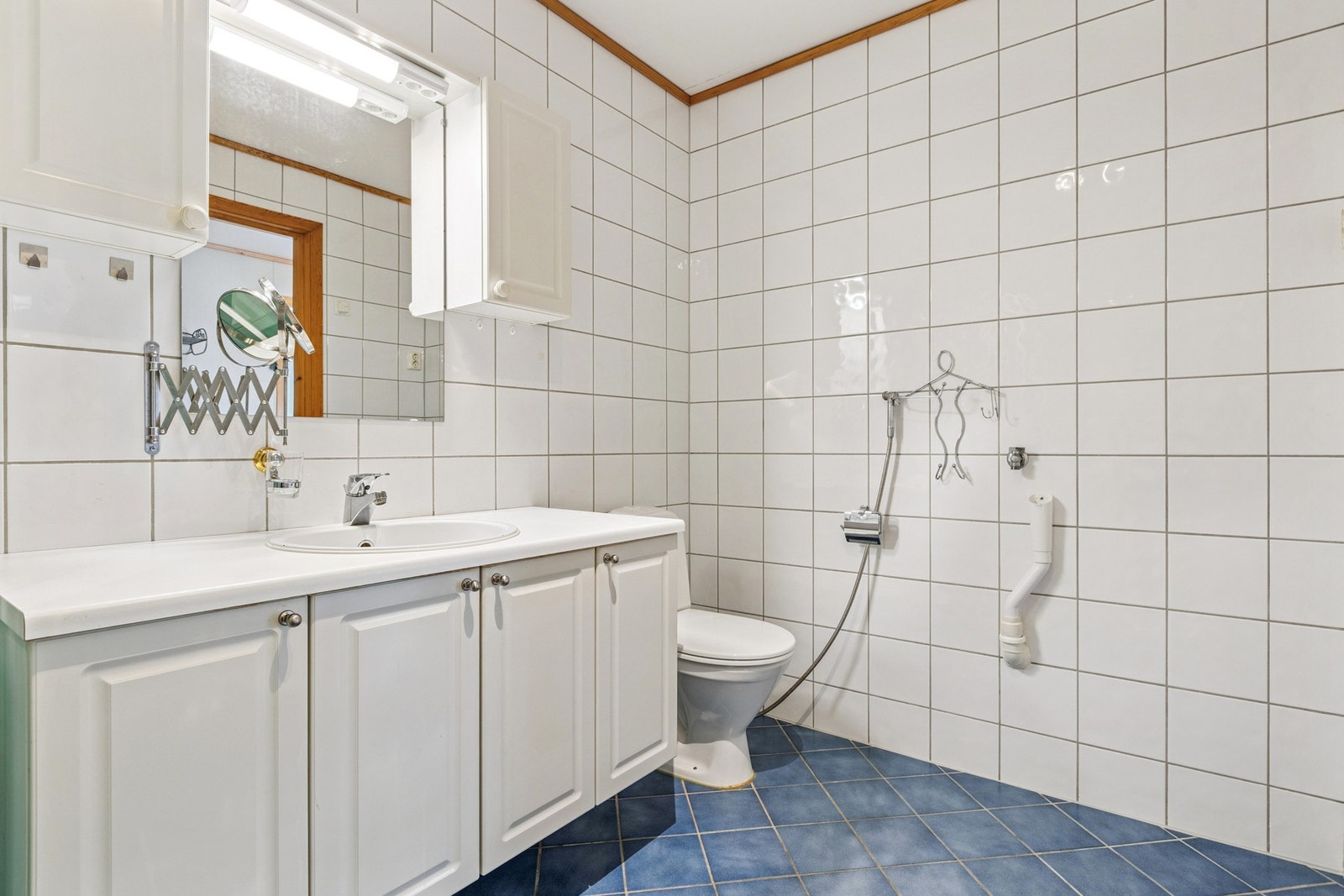 Badet er utstyrt med vegghengt servantinnredning, speil med overlys, dusjhjørne og toalett. Galleribilde