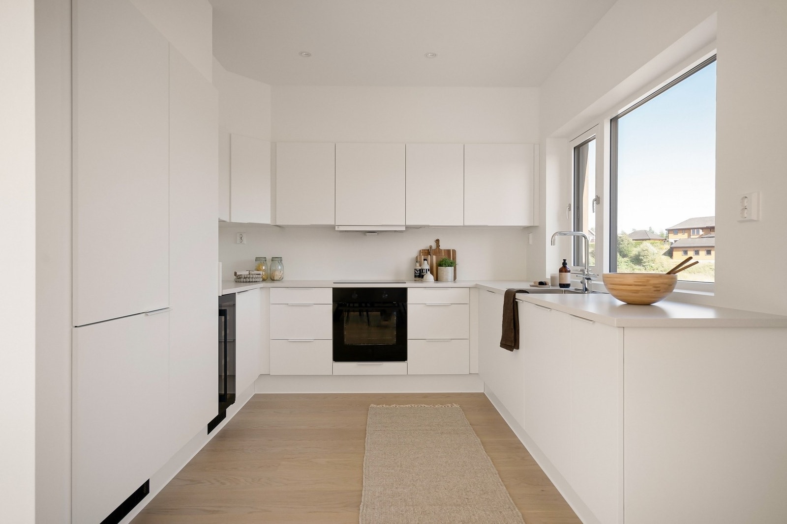 Stilrent kjøkken fra JKE Design med benkeplate av eik og integrerte hvitevarer. Galleribilde