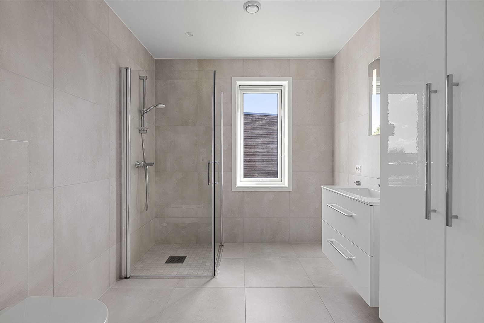 Flott bad med tidsriktige store fliser i delikat farge Galleribilde