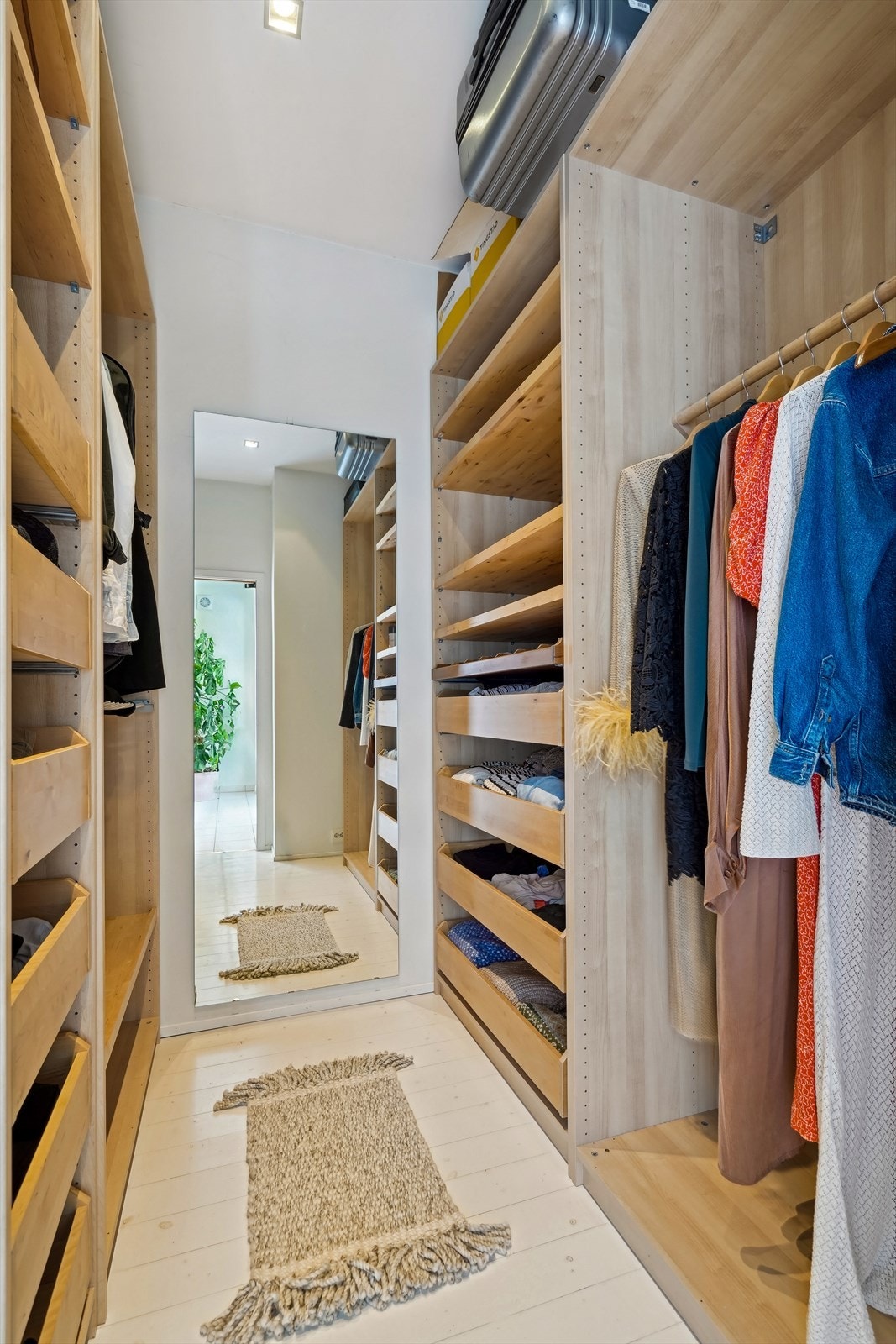 Lys og romslig garderoberom med stor fast innredning og gode oppbevaringsmuligheter Galleribilde