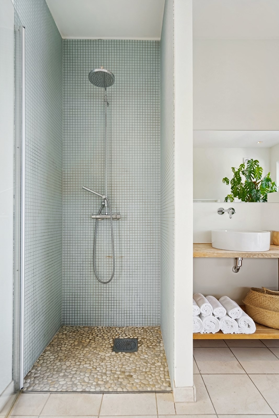 Dusjnisje med glassdør. Det er lagt rullesteiner i dusjsonen samt mosaikkfliser på vegger. Gulvene har limestone fliser som er behagelige å gå på Galleribilde