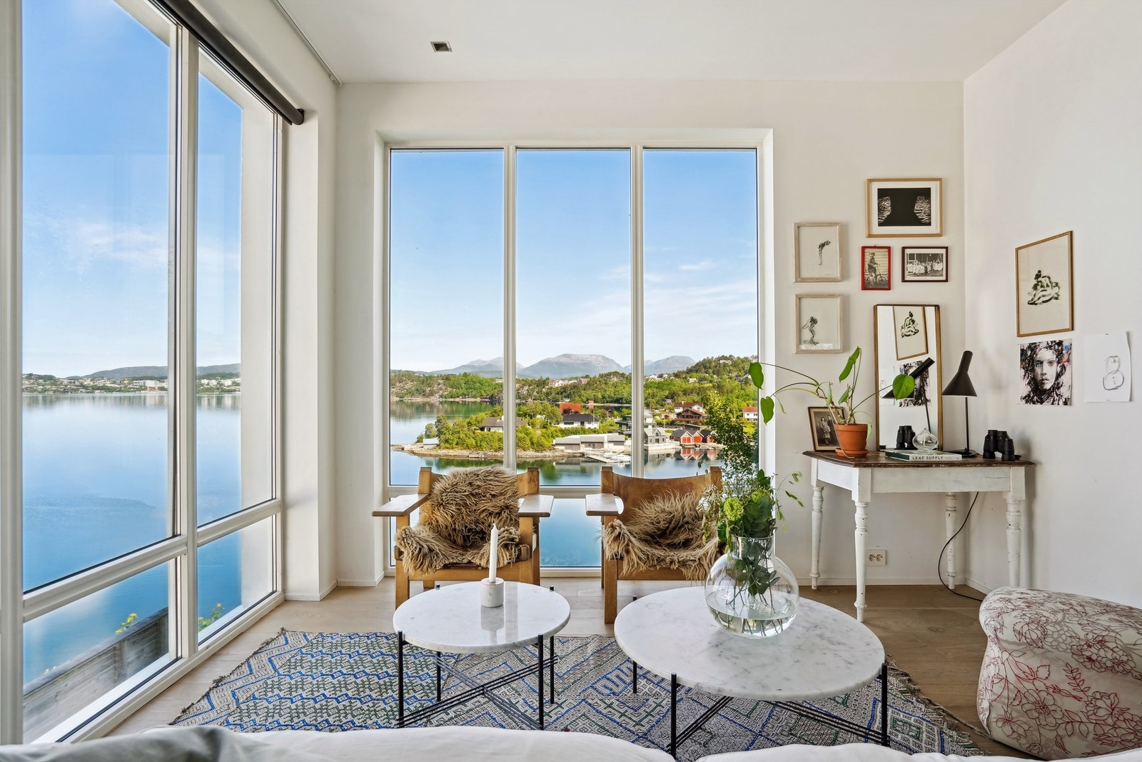 Stue med lyse overflater og store vindusflater, samt flott utsikt mot sjøen Galleribilde