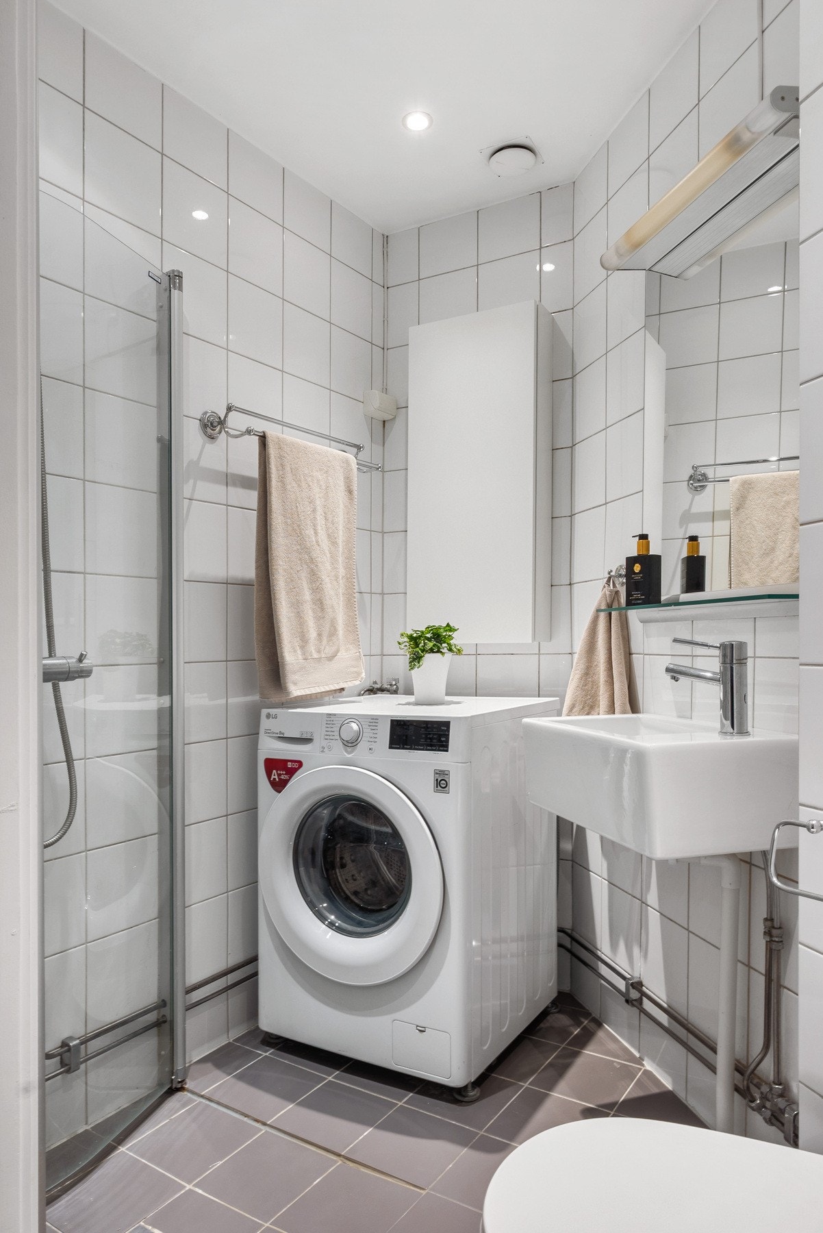 Bad med fliser på både gulv og vegger, innfelte downlights, vegghengt toalett, servant med speil og lys. Galleribilde