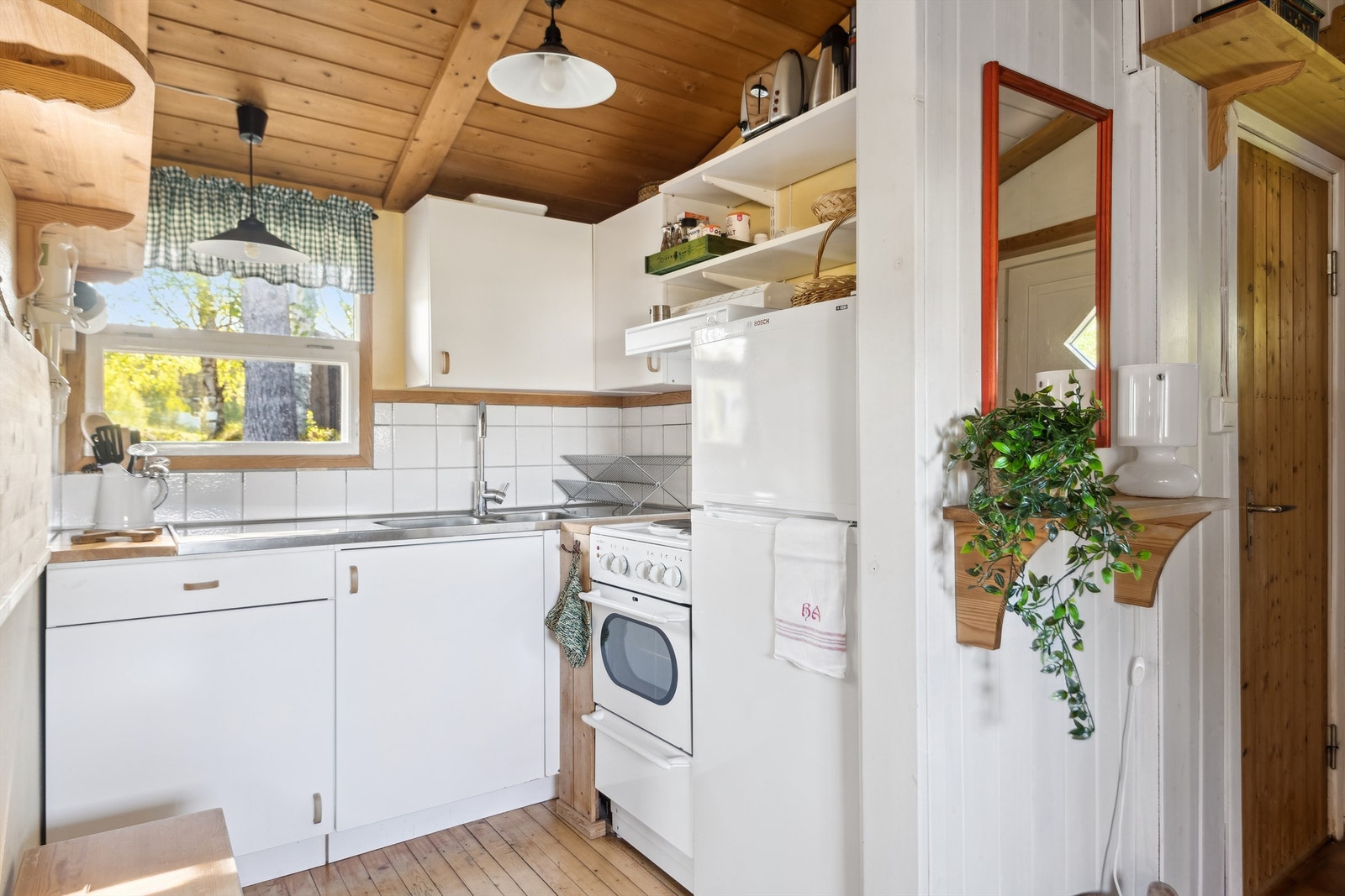 Funksjonell kjøkkeninnredning, fliser mellom over- og underskap, og åpen løsning for hvitevarer Galleribilde