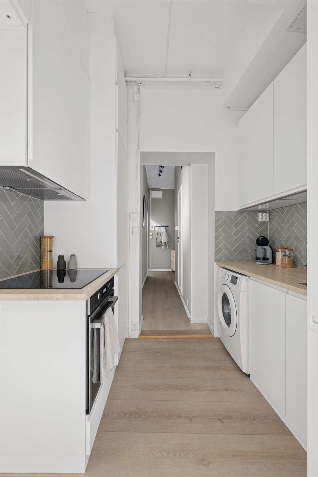IKEA kjøkkeninnredning fra 2019/2020 med slette, lakkerte fronter og laminat benkeplate med delikat flislagt vegg i grønntoner. Galleribilde