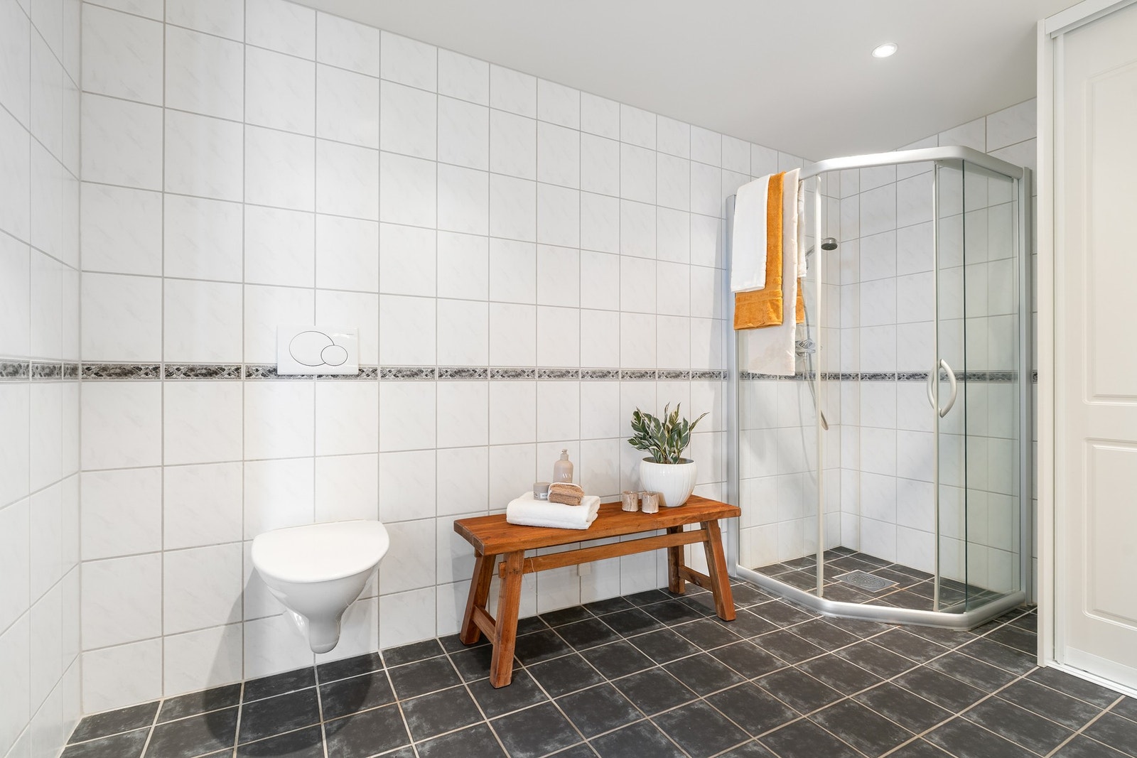 Vegghengt toalett, dusjnisje vask og opplegg for vaskemaskin på badet. Galleribilde