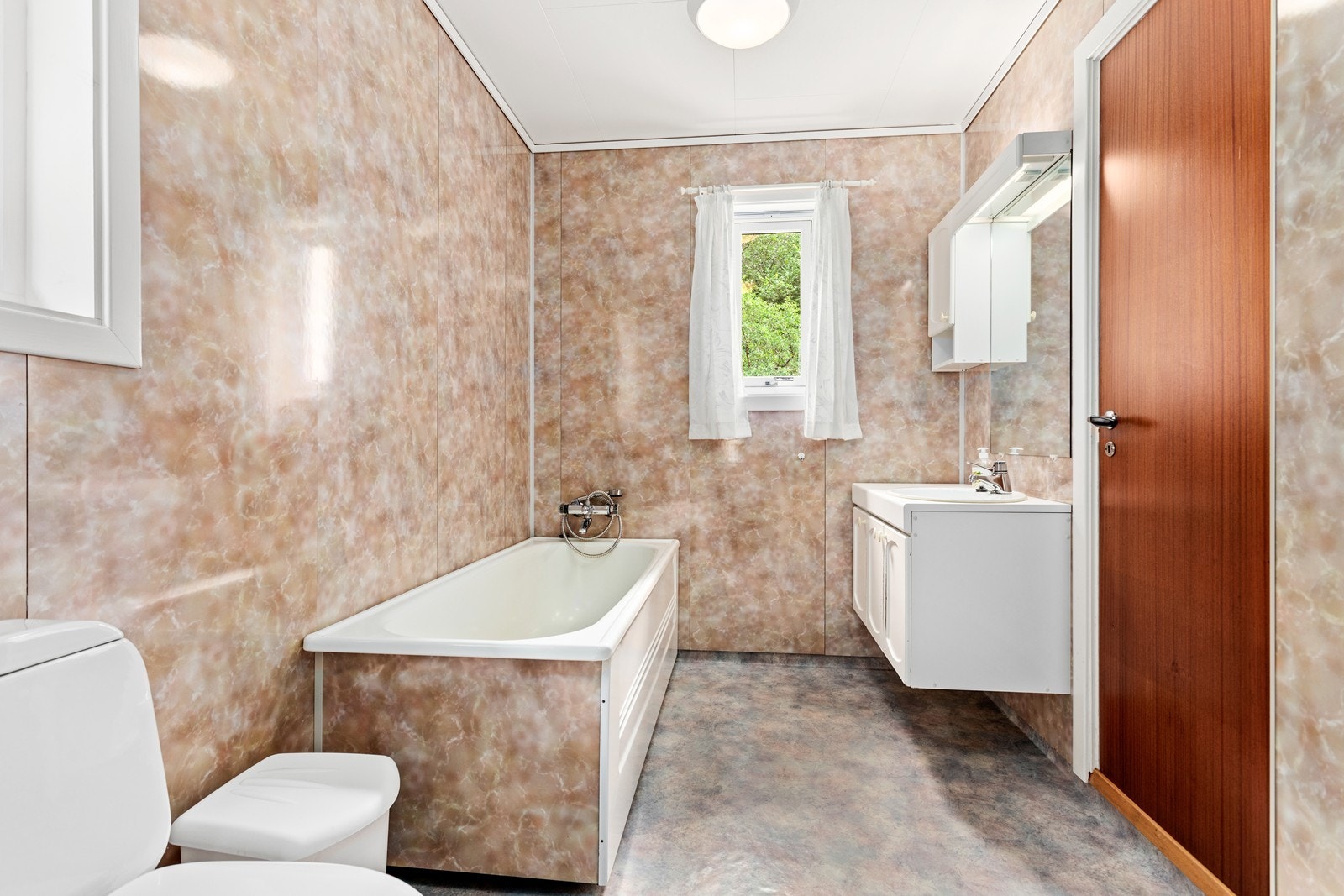 Badet er utstyrt med baderomsinnreiing, badekar med dusjgarnityr og toalett. Galleribilde