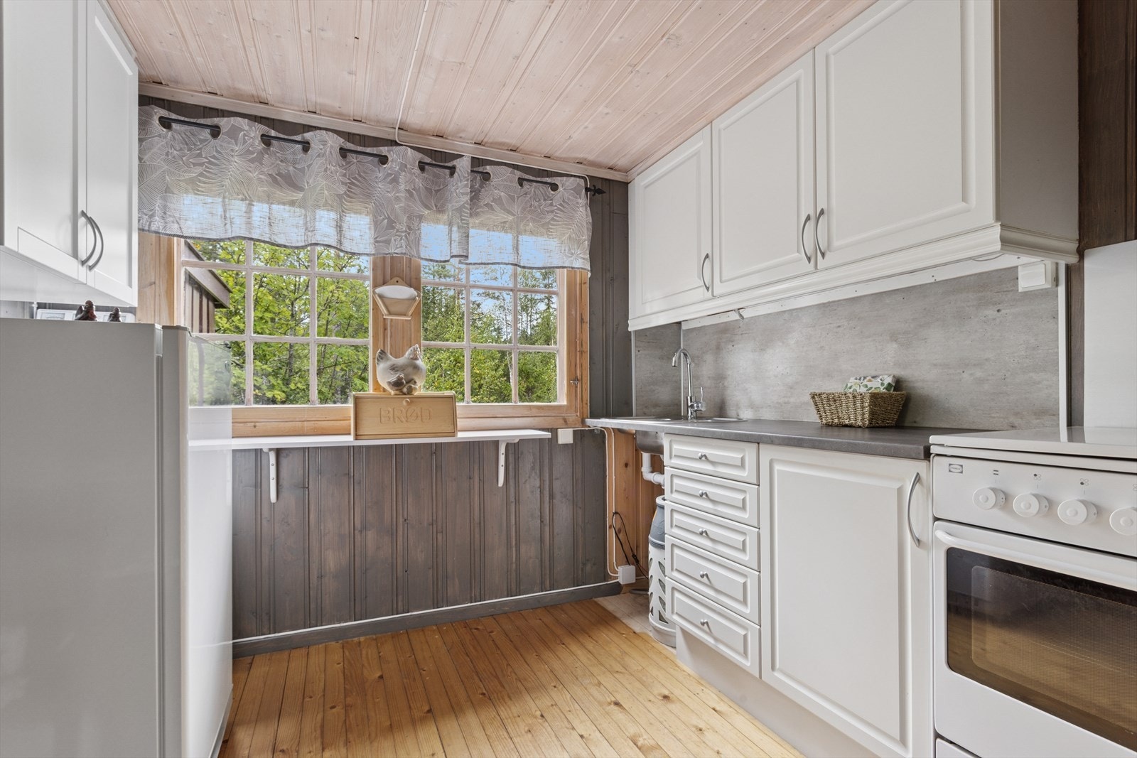 Lys og fin kjøkkeninnredning med profilerte fronter. Kjøleskap og komfyr. Galleribilde