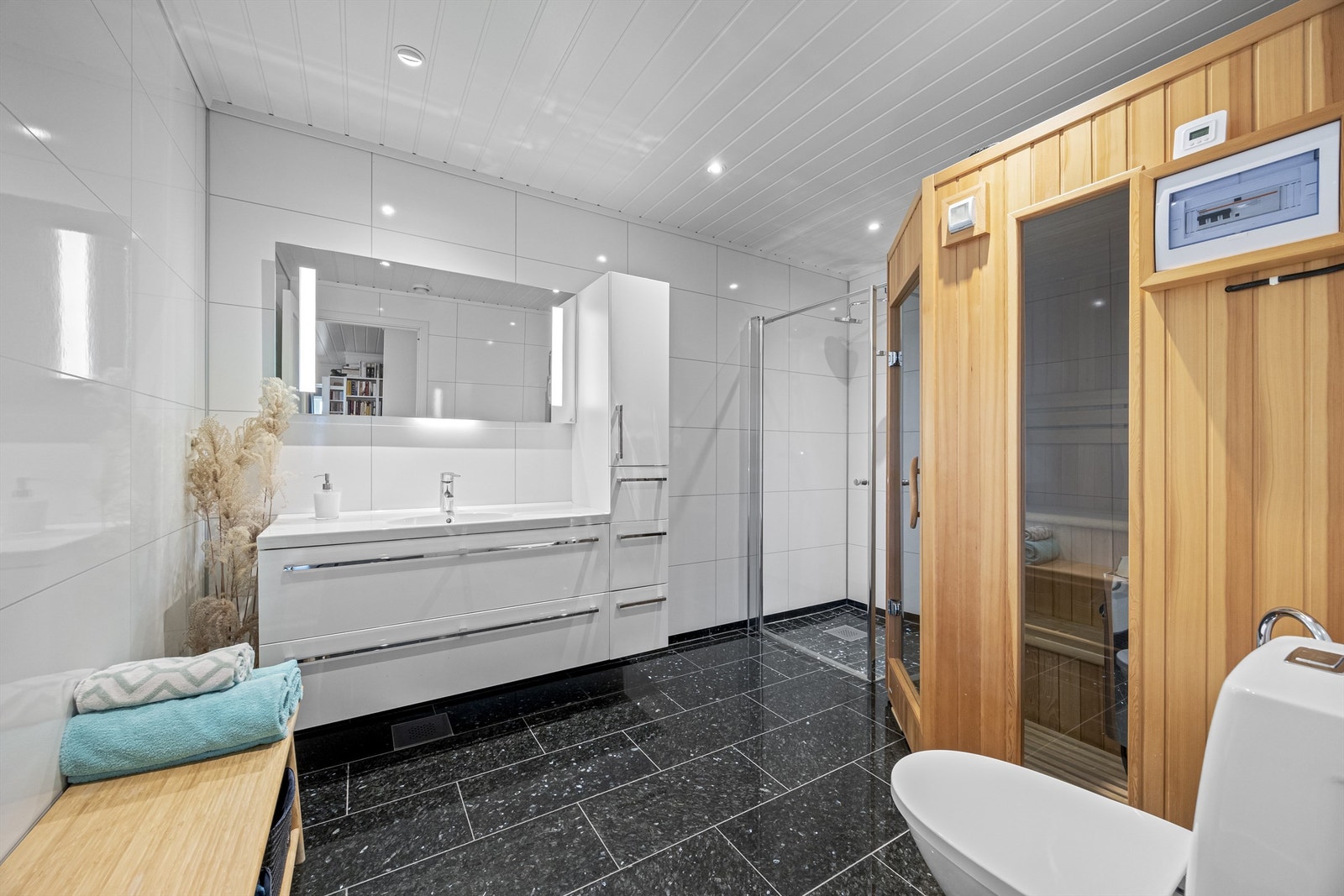 Baderom i underetasjen med egen badstue, dusjhjørne, toalett, servantinnredning og speil med innebygd lys. Galleribilde